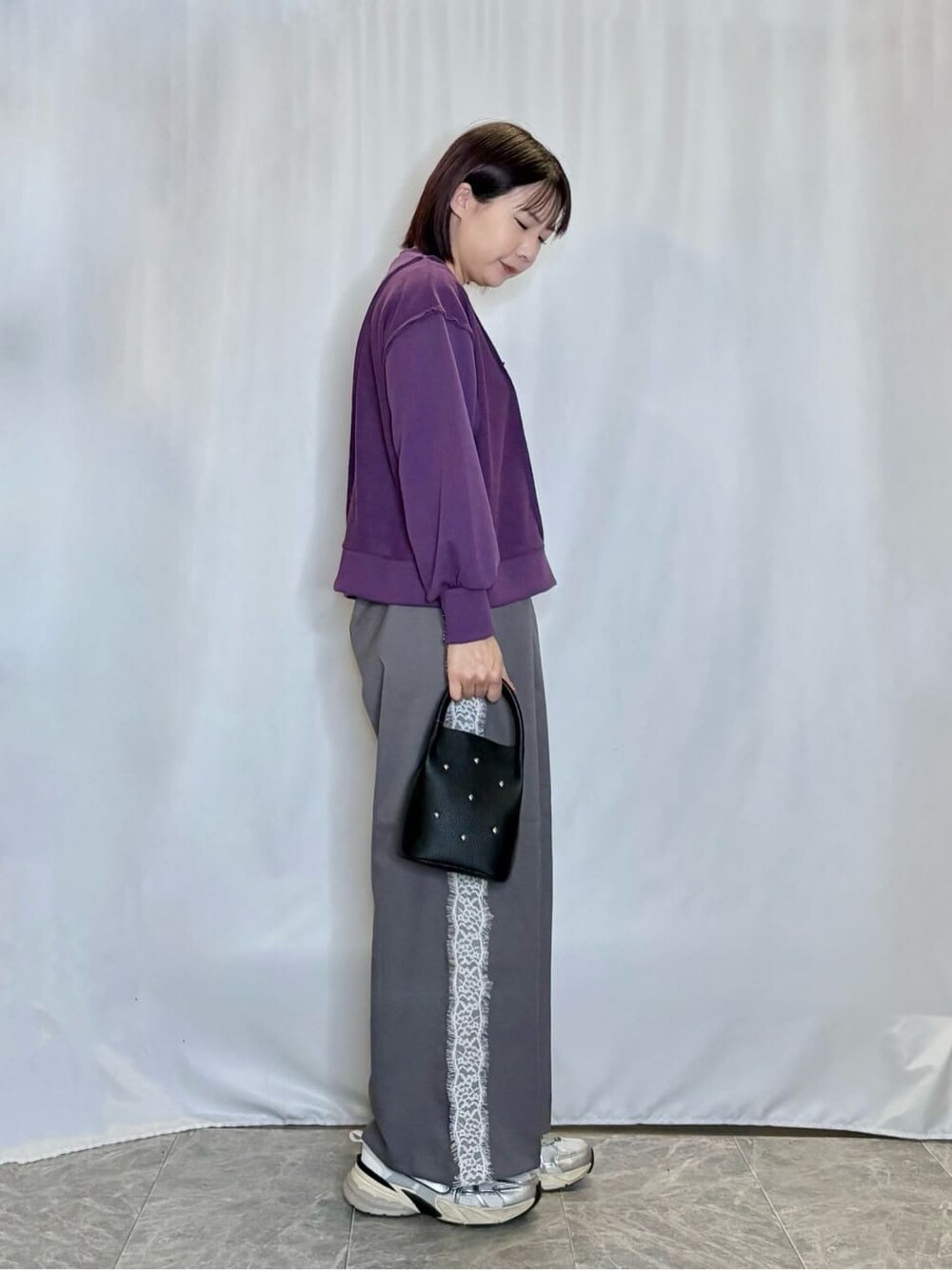 パープル系のスウェット、グレー系のその他パンツ、ブラック系のショルダーバッグを着用したレディースの秋コーディネートの2枚目の写真