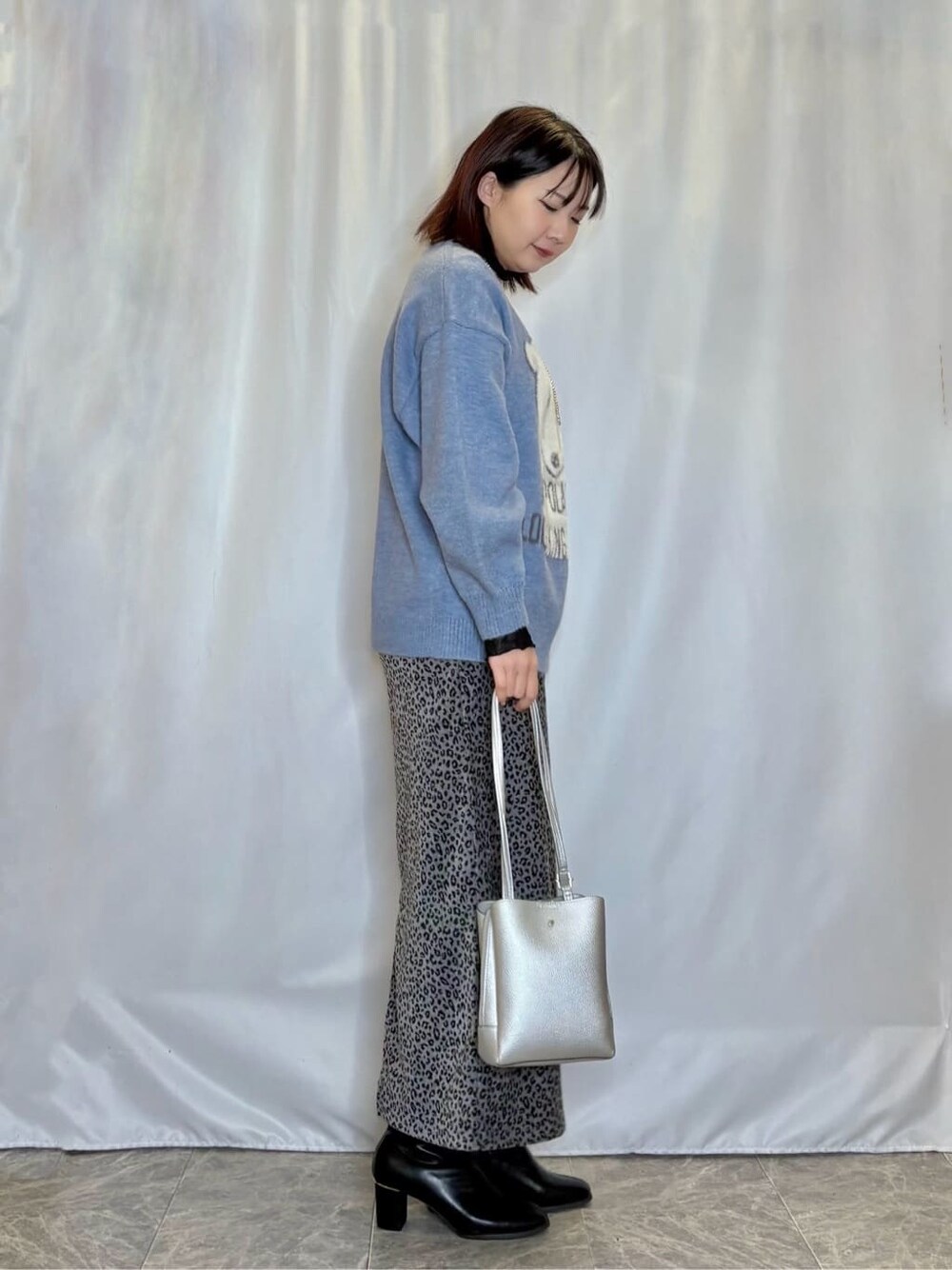 ブルー系のニット/セーター、ブラック系のTシャツ/カットソー、グレー系のスカートを着用したレディースの冬コーディネートの2枚目の写真