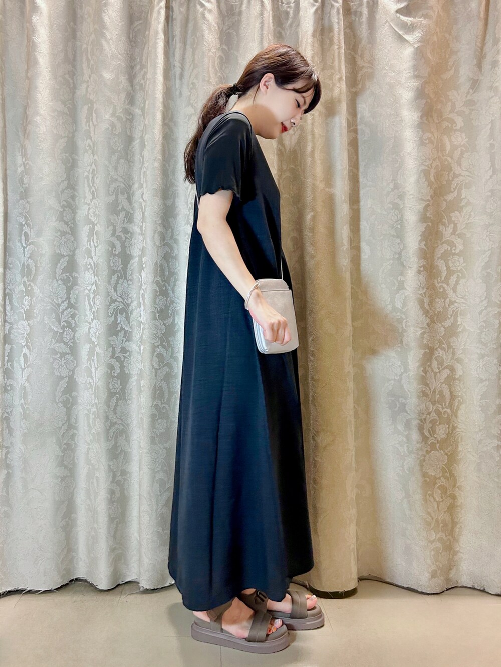 グレー系のワンピース、ブラック系のTシャツ/カットソー、シルバー系のショルダーバッグを着用したレディースの夏コーディネートの2枚目の写真