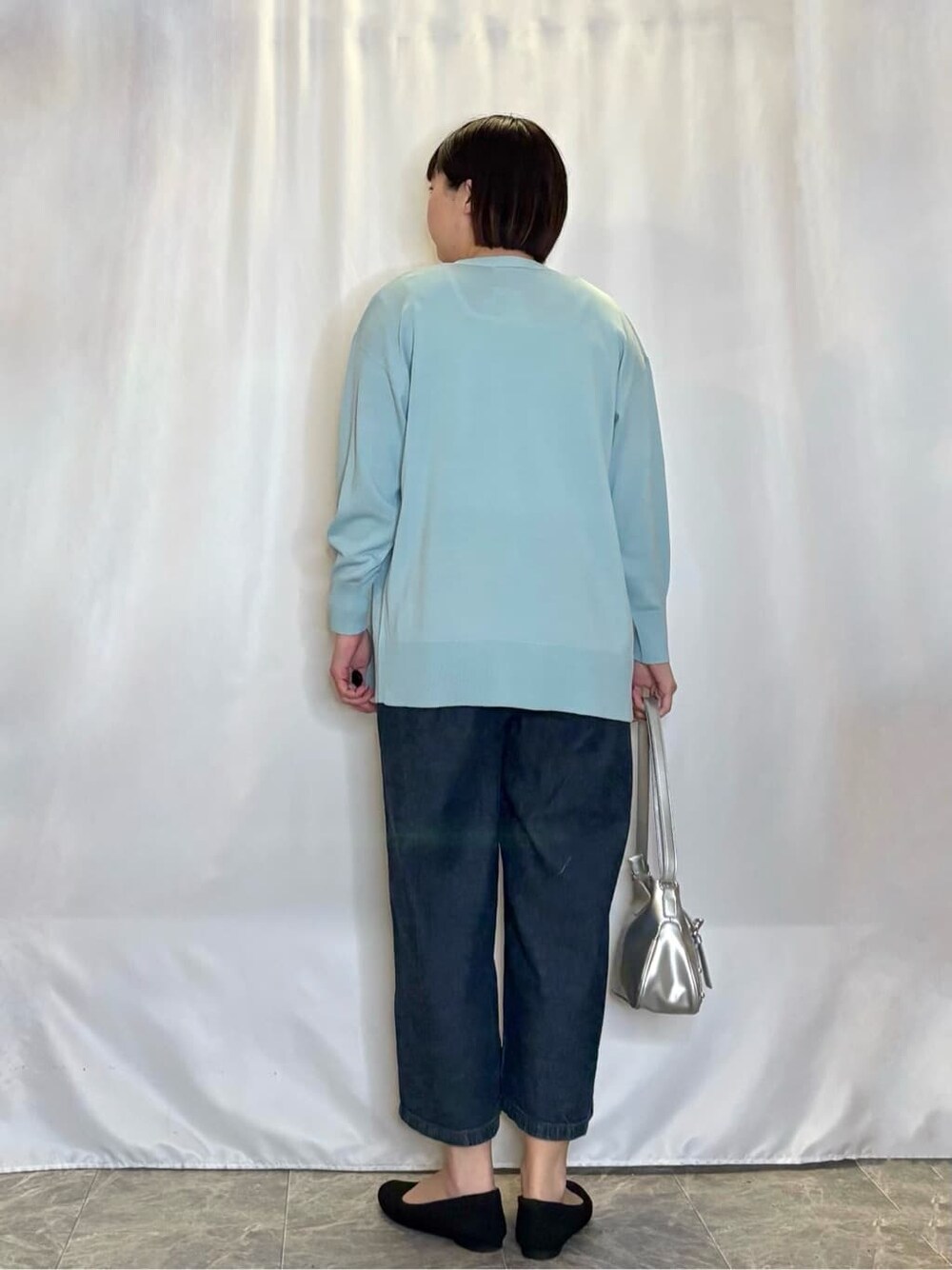 ブルー系のデニムパンツ、ブラック系のワンピース、グリーン系のカーディガン/ボレロを着用したレディースの春コーディネートの3枚目の写真