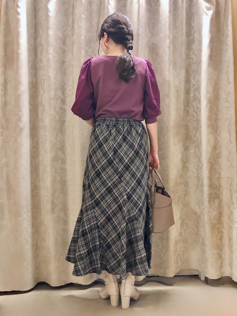 ベージュ系のトートバッグ、ホワイト系のブーツ、ブラック系のスカートを着用したレディースの秋コーディネートの3枚目の写真