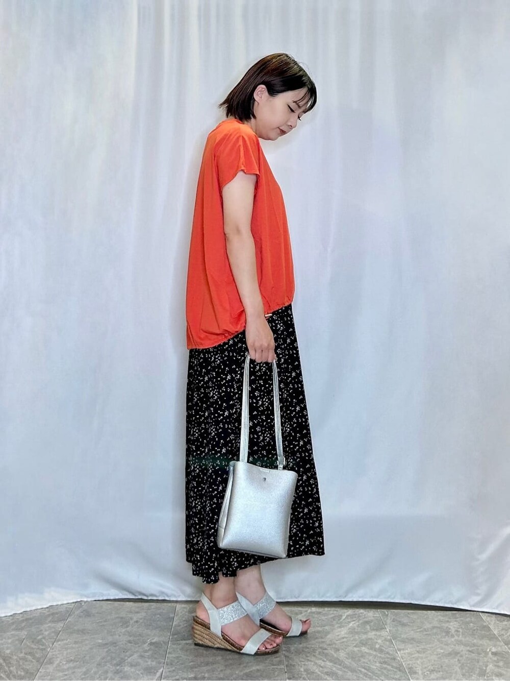 オレンジ系のTシャツ/カットソー、ブラック系のその他パンツ、シルバー系のサンダルを着用したレディースの夏コーディネートの2枚目の写真