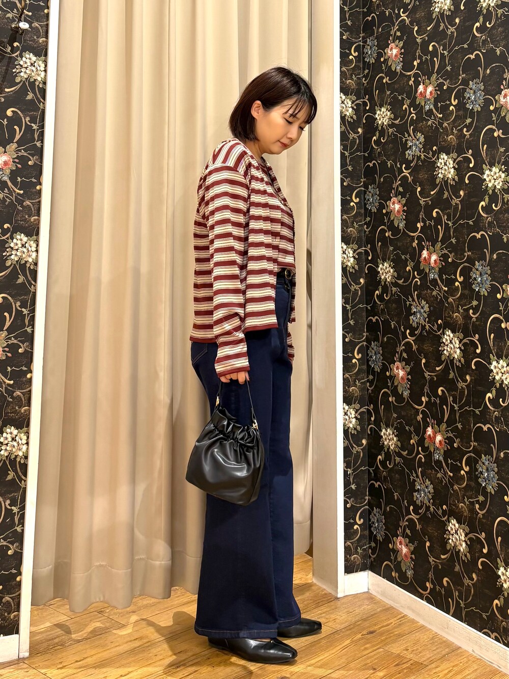 ブルー系のデニムパンツ、ブラック系のショルダーバッグ、ゴールド系のネックレスを着用したレディースの秋コーディネートの2枚目の写真