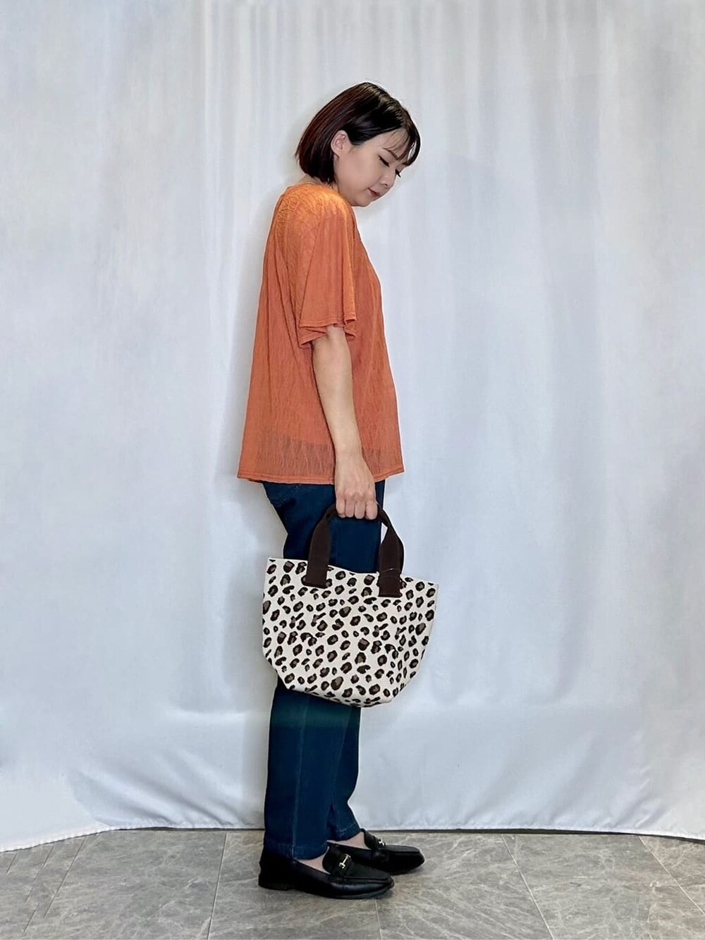 レッド系のTシャツ/カットソー、ブルー系のデニムパンツ、ブラック系のその他シューズを着用したレディースの秋コーディネートの2枚目の写真