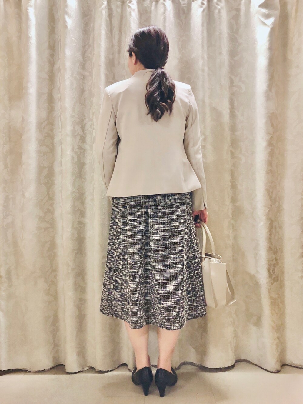 グレー系のトートバッグ、ベージュ系のノーカラージャケット、ブラック系のパンプスを着用したレディースの春コーディネートの3枚目の写真