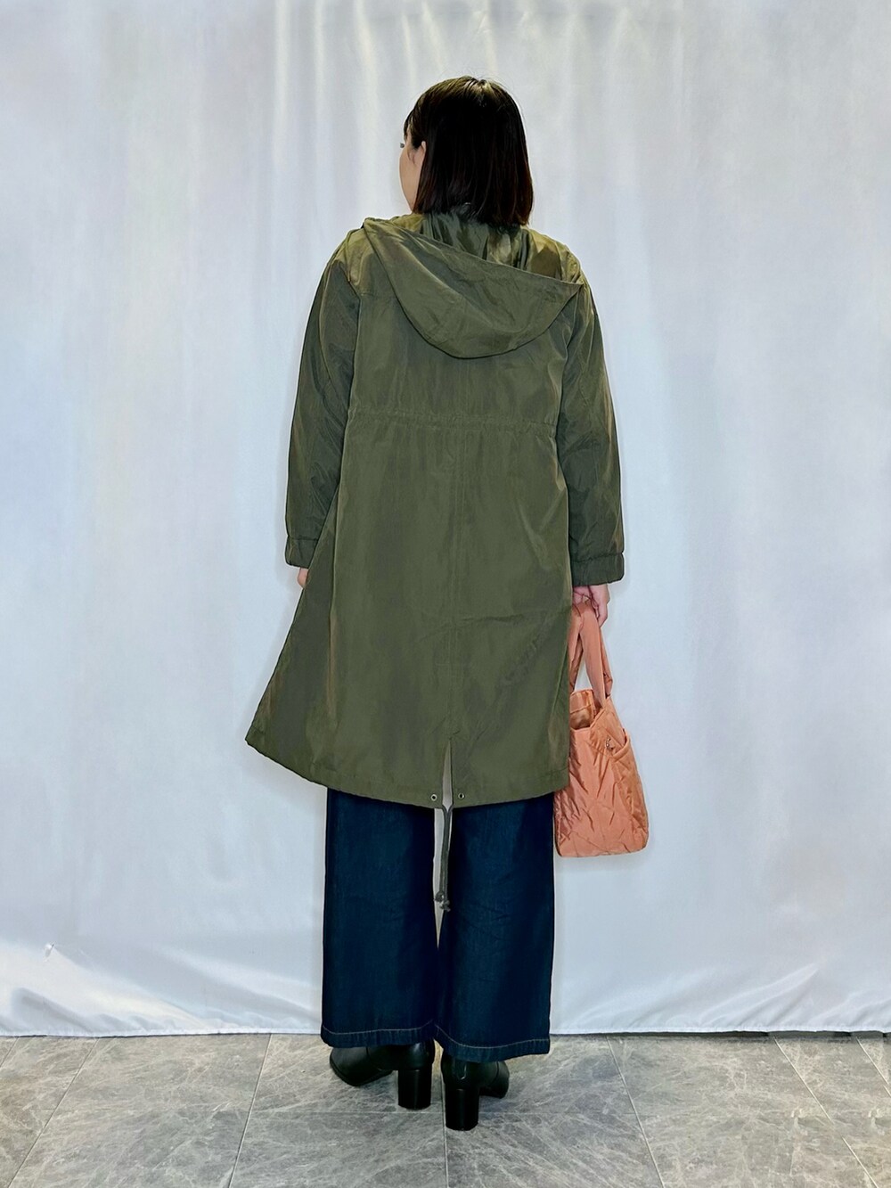 オレンジ系のトートバッグ、ブラック系のブーツ、ブルー系のデニムパンツを着用したレディースの秋コーディネートの3枚目の写真