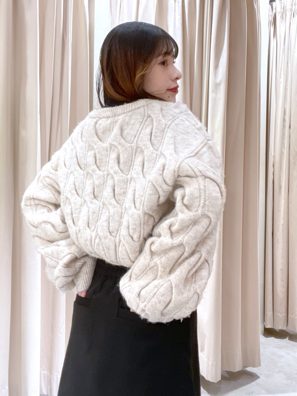 ホワイト系のニット/セーター、ブラック系のスカートを着用したレディースの冬コーディネートの2枚目の写真