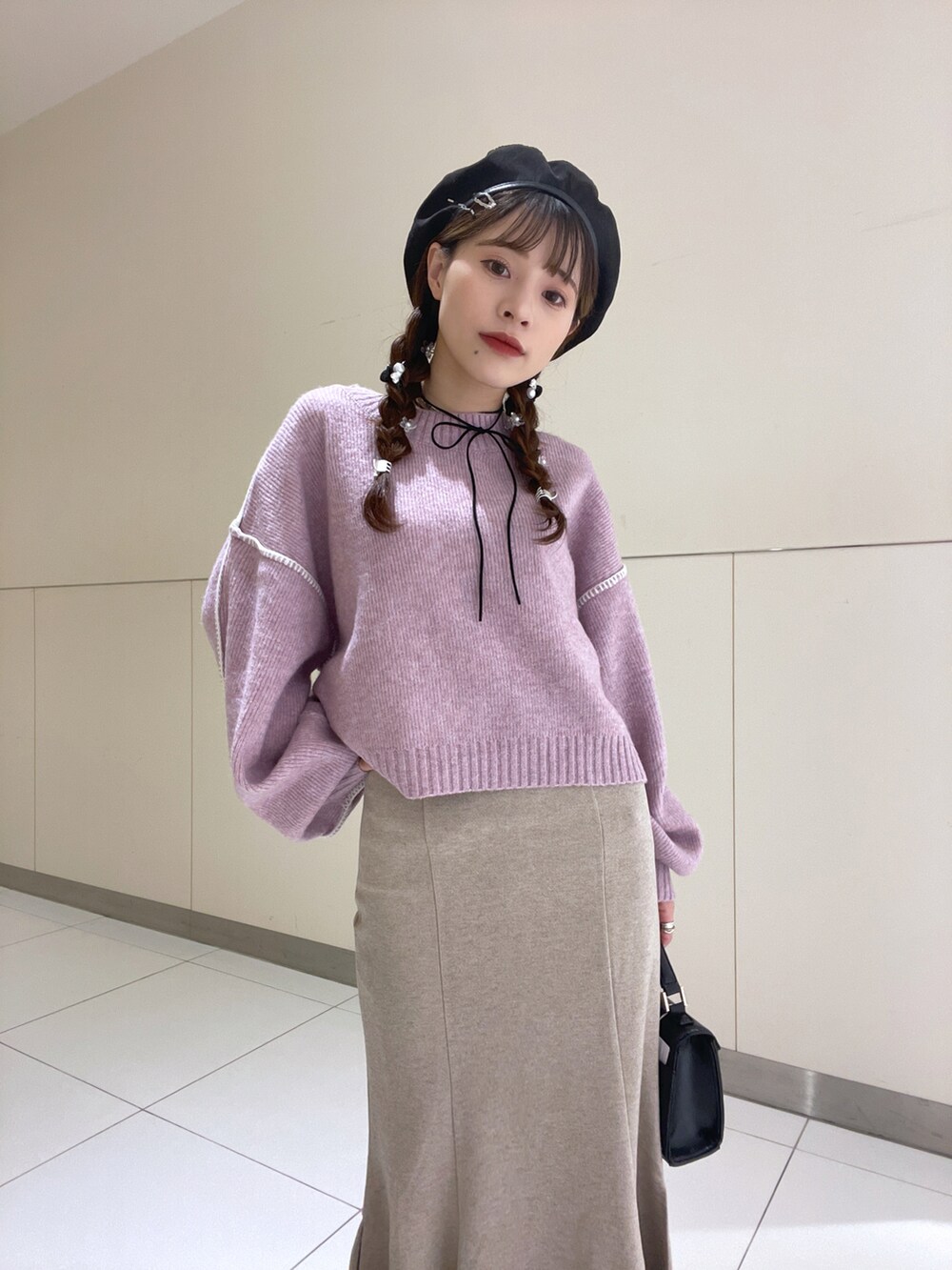 ブラック系のハンドバッグ、パープル系のニット/セーター、ベージュ系のスカートを着用したレディースの秋コーディネートの2枚目の写真