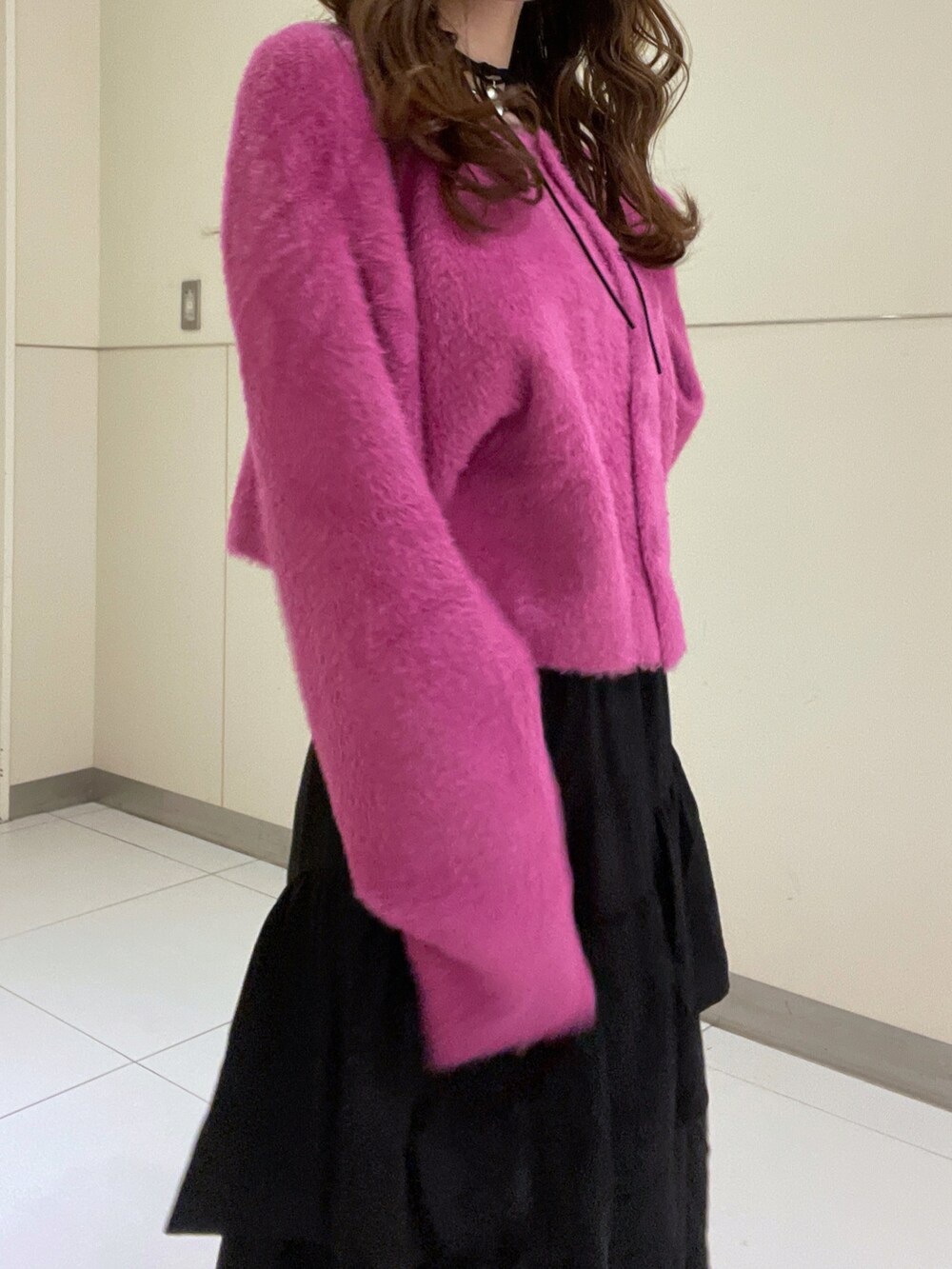 ブラック系のスカート、ピンク系のニット/セーターを着用したレディースの秋コーディネートの2枚目の写真