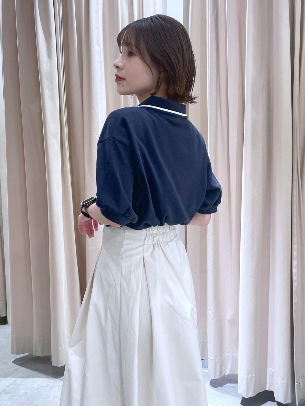 ブルー系のポロシャツ、ホワイト系のスカートを着用したレディースの春コーディネートの2枚目の写真