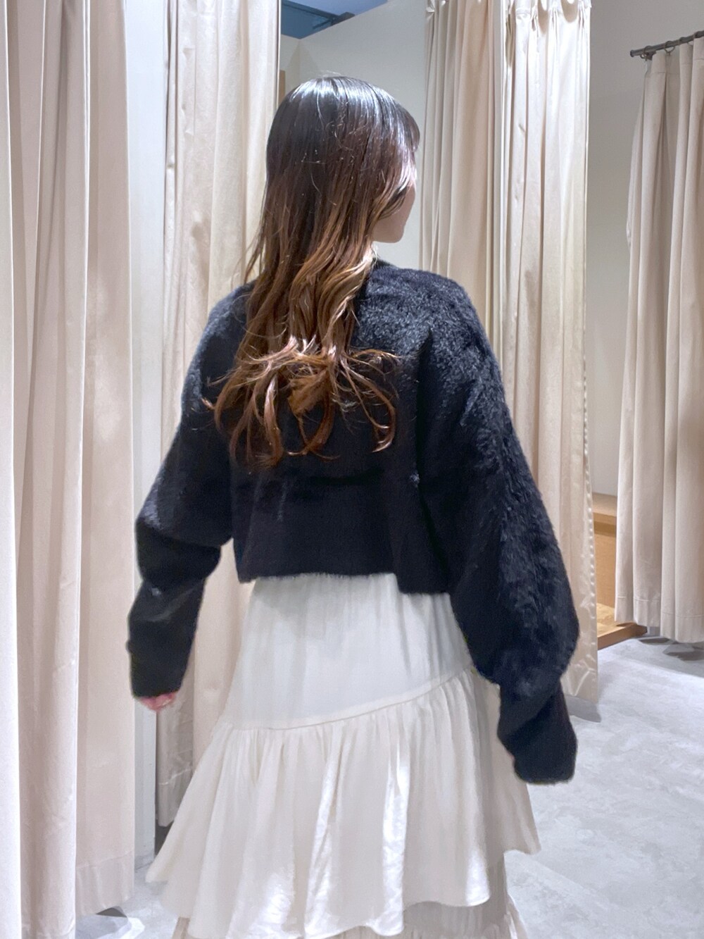 ブラック系のカーディガン/ボレロ、ホワイト系のスカートを着用したレディースの冬コーディネートの2枚目の写真