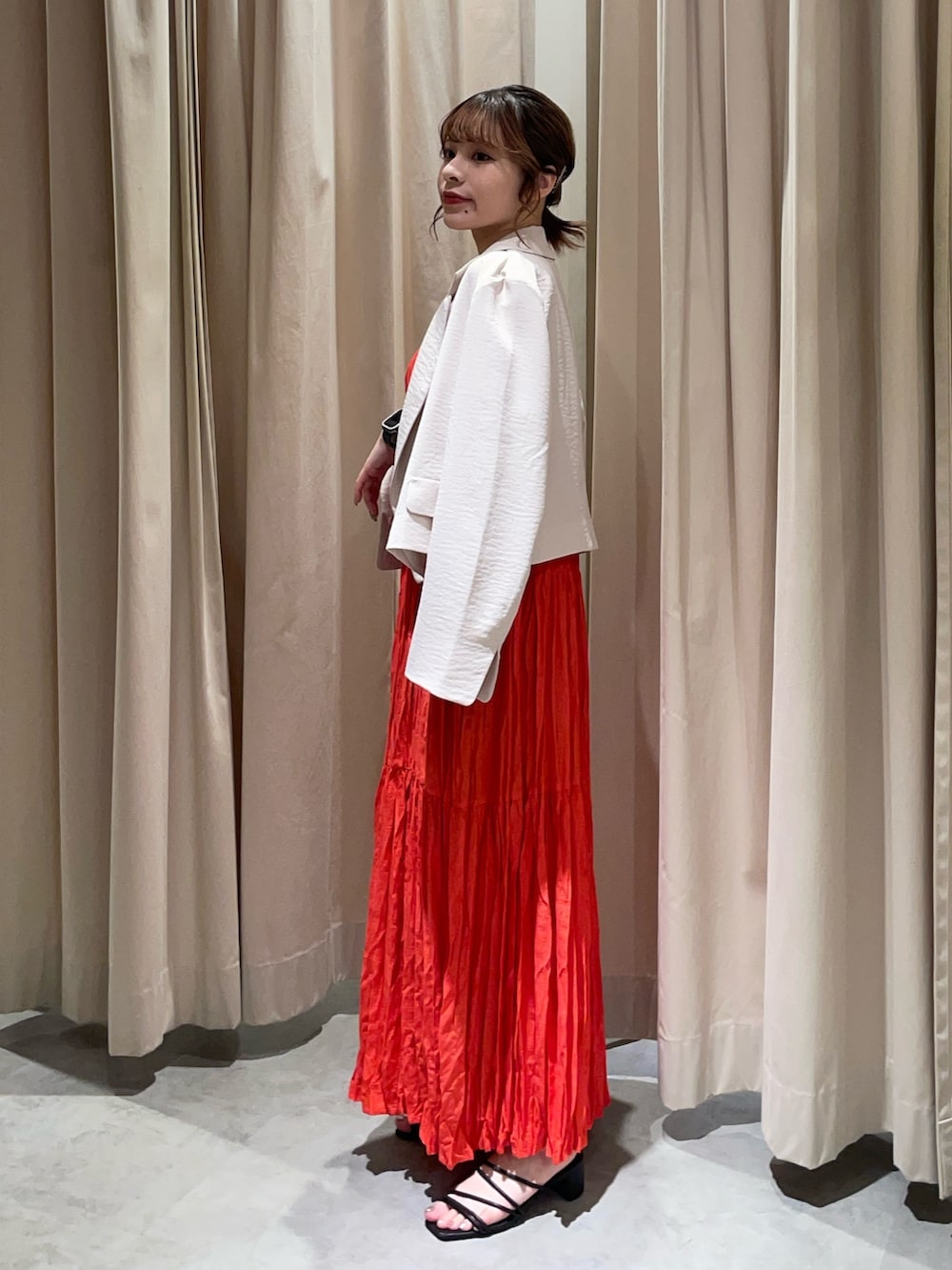 レッド系のワンピース、ホワイト系のテーラードジャケットを着用したレディースの夏コーディネートの2枚目の写真