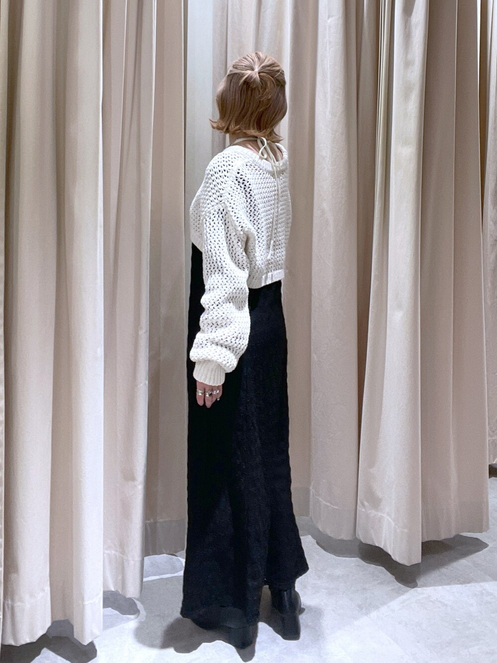 ベージュ系のニット/セーター、ブラック系のワンピースを着用したレディースの春コーディネートの2枚目の写真