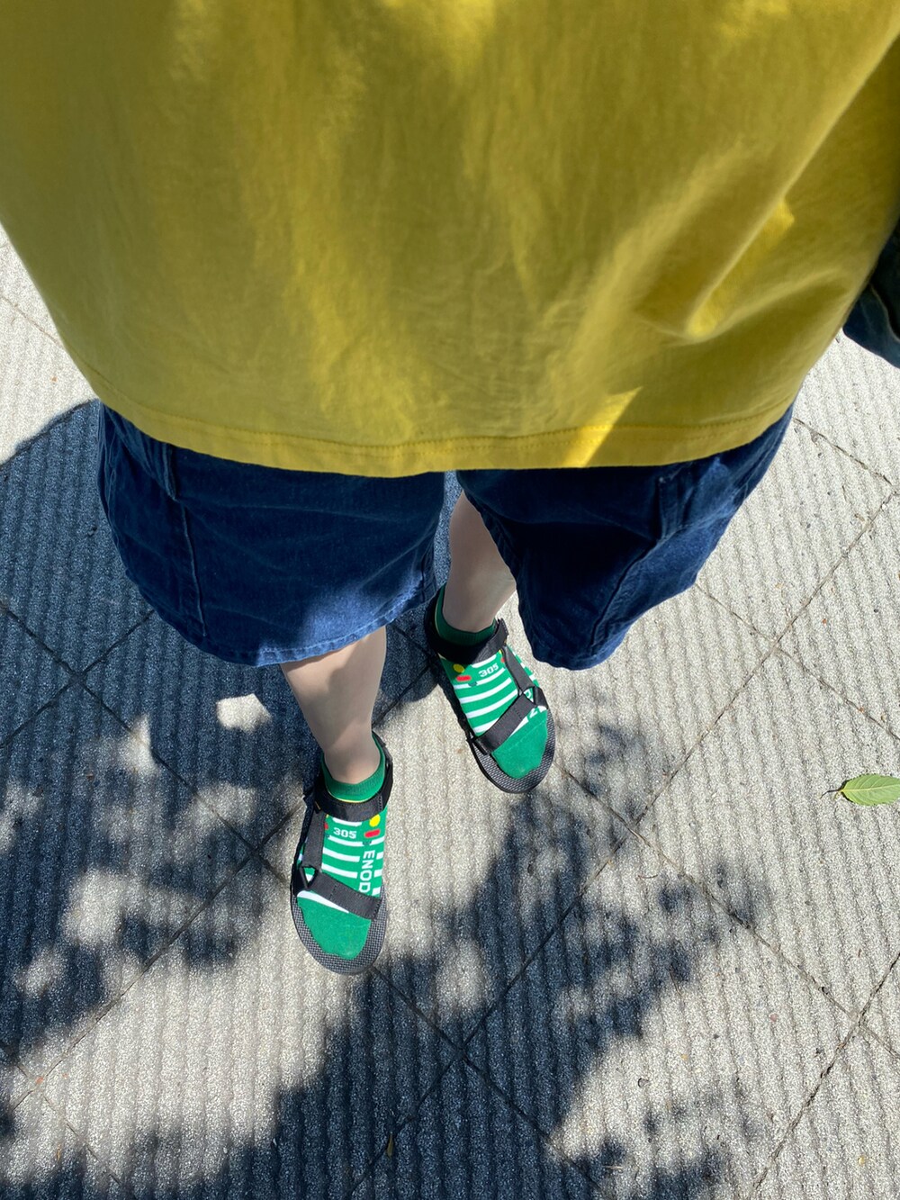 イエロー系のTシャツ/カットソー、ブラック系のハットを着用したレディースの夏コーディネートの2枚目の写真