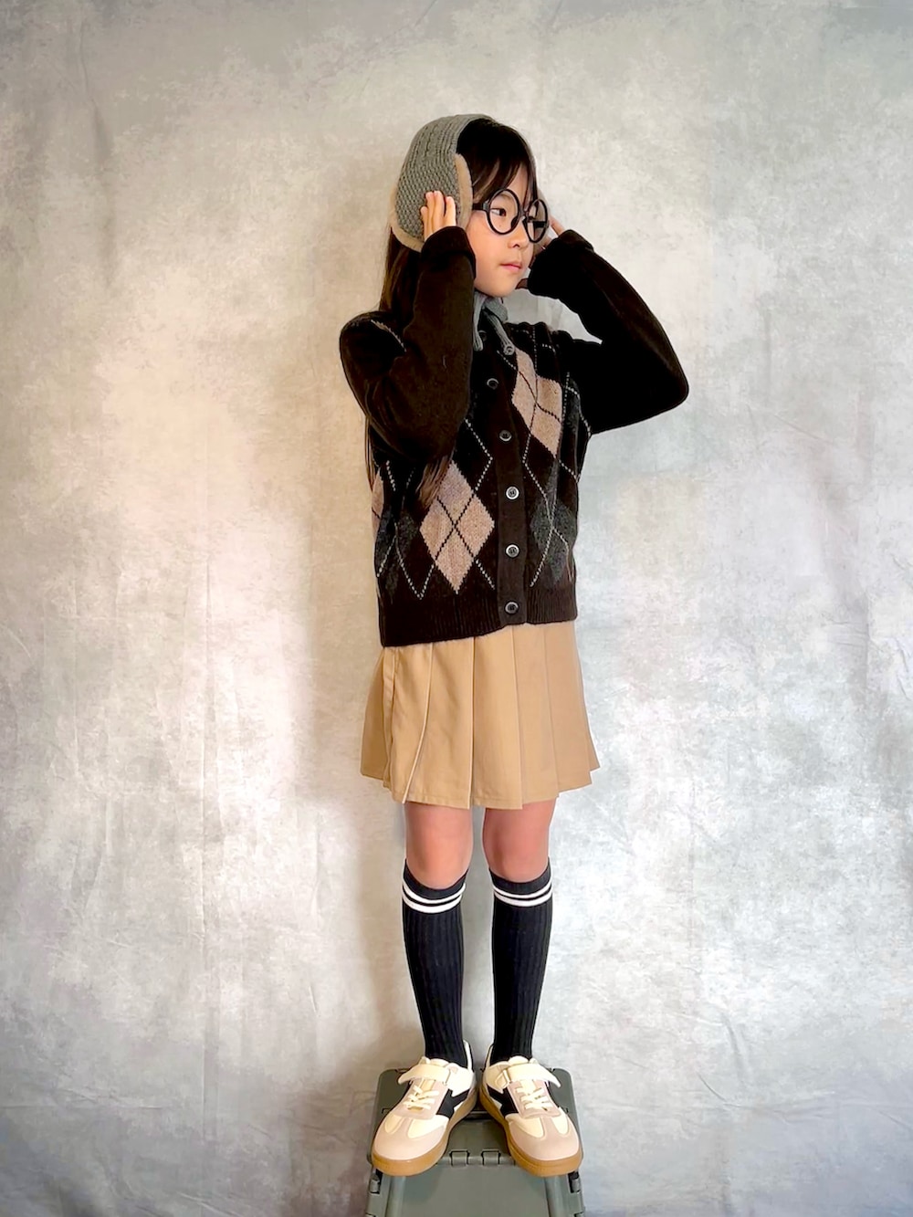 ブラウン系のカーディガン/ボレロ、ベージュ系のスカート、グレー系のイヤーマフを着用したキッズの秋コーディネートの2枚目の写真