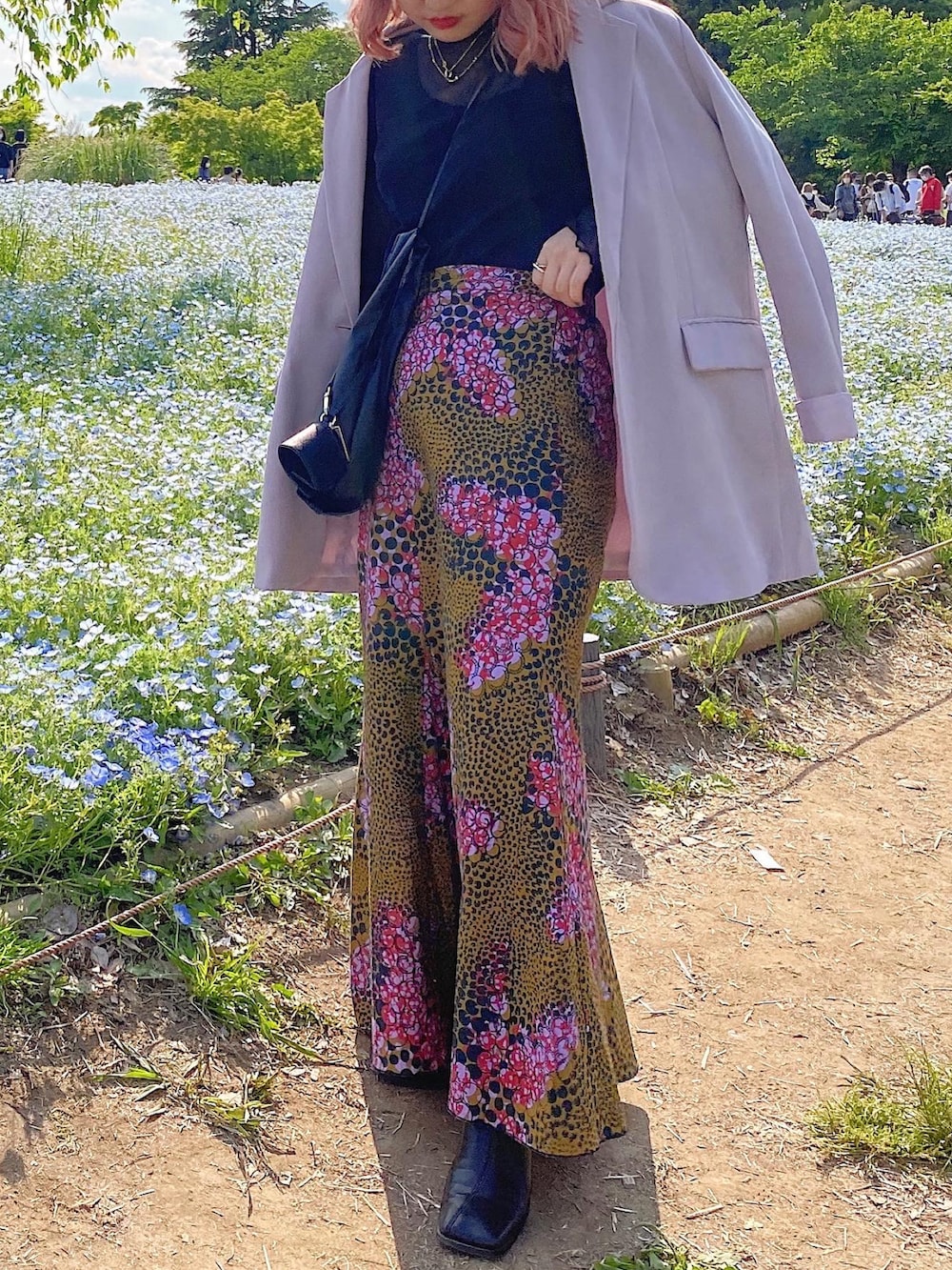 ピンク系のスカート、ブラック系のブーツ、パープル系のテーラードジャケットを着用したレディースの夏コーディネートの2枚目の写真