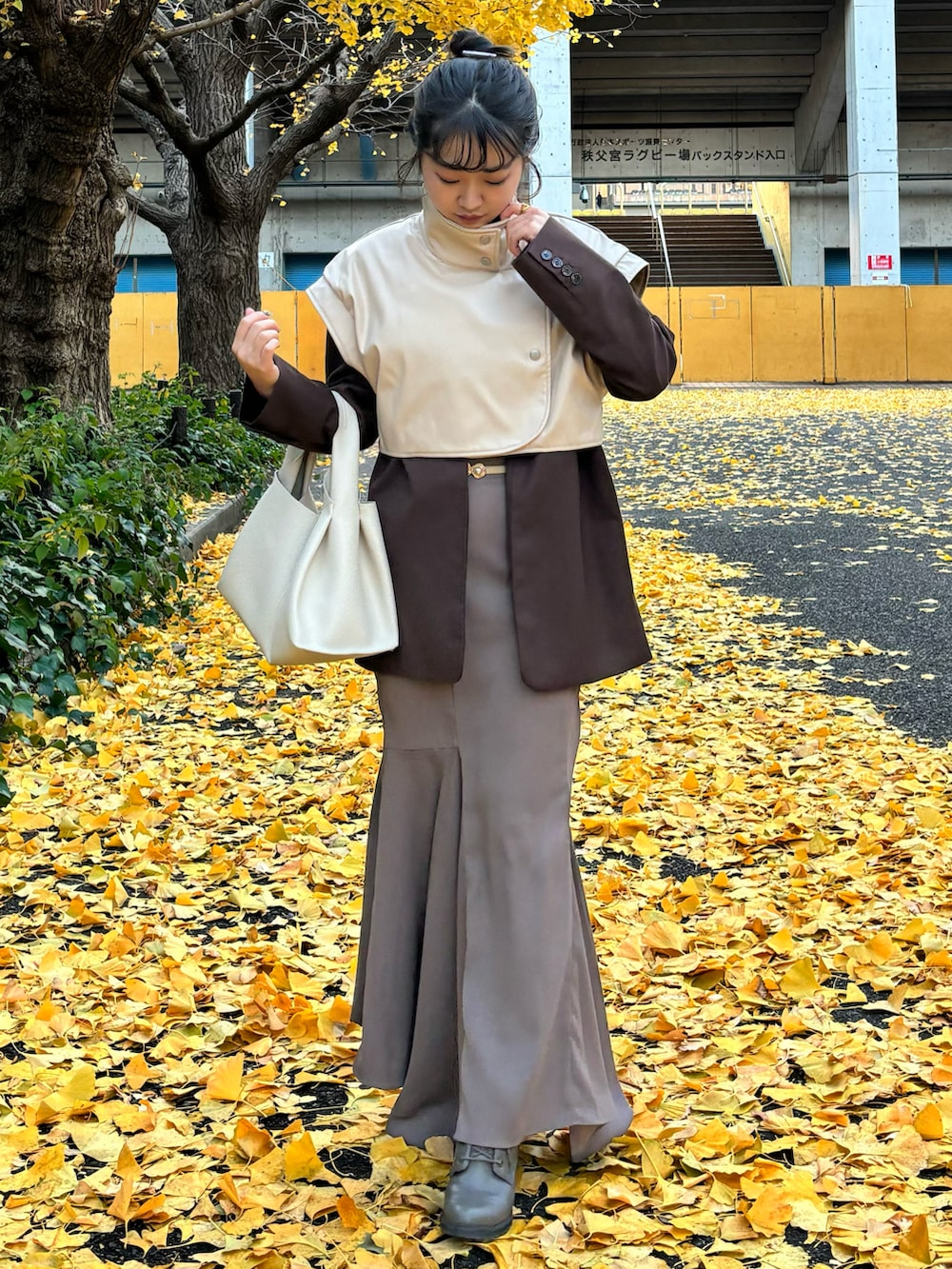 ホワイト系のハンドバッグ、ベージュ系のスカート、ホワイト系のベストを着用したレディースの冬コーディネートの2枚目の写真