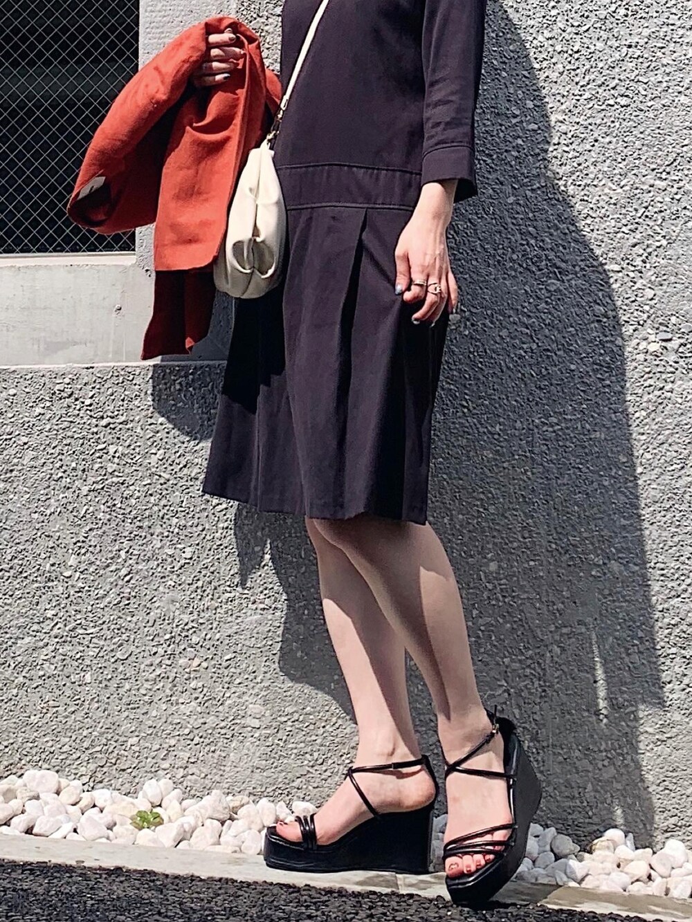 ブラック系のワンピース、ブラック系のサンダル、オレンジ系のノーカラージャケットを着用したレディースの夏コーディネートの2枚目の写真