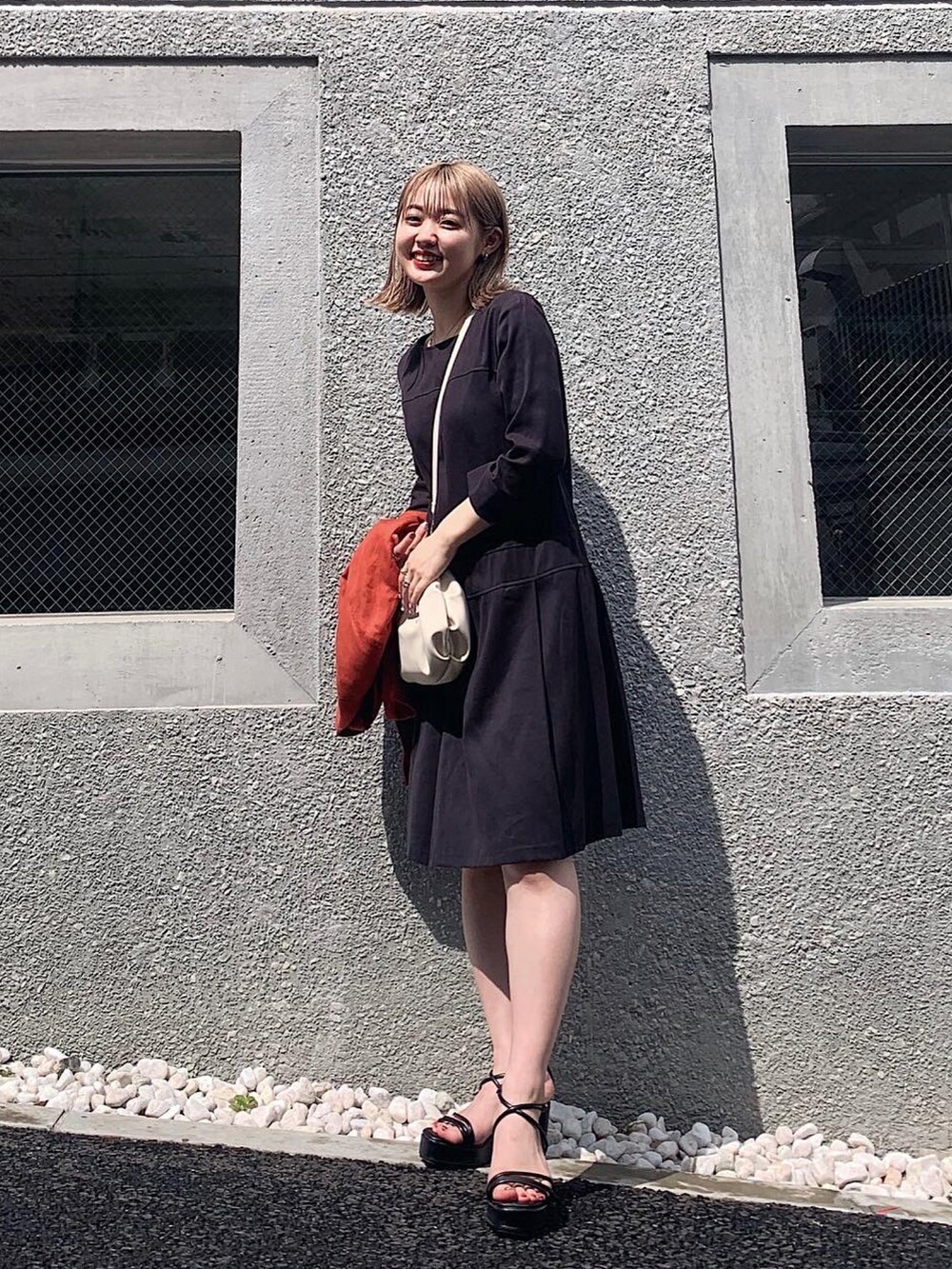 ブラック系のワンピース、ブラック系のサンダル、オレンジ系のノーカラージャケットを着用したレディースの夏コーディネートの3枚目の写真