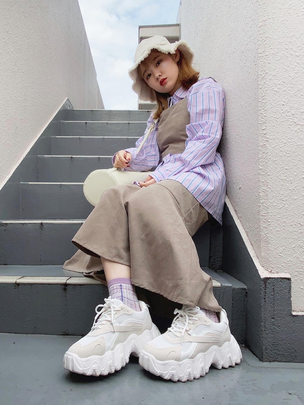 ベージュ系のワンピース、ホワイト系のバッグ、ホワイト系のスニーカーを着用したレディースの秋コーディネートの4枚目の写真