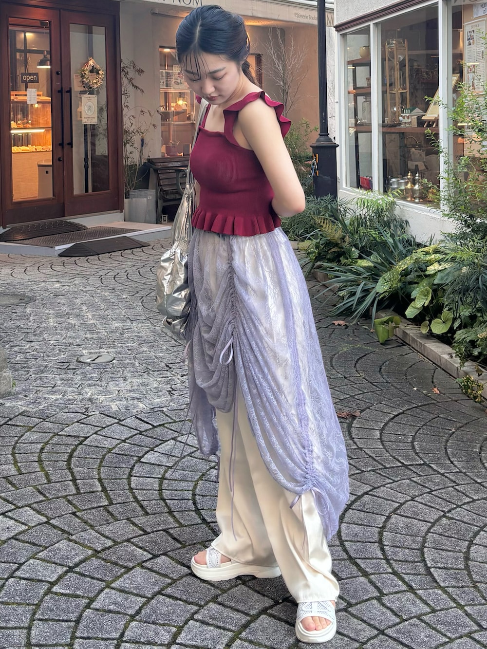 レッド系のトップス、パープル系のスカート、ホワイト系のサンダルを着用したレディースの秋コーディネートの3枚目の写真