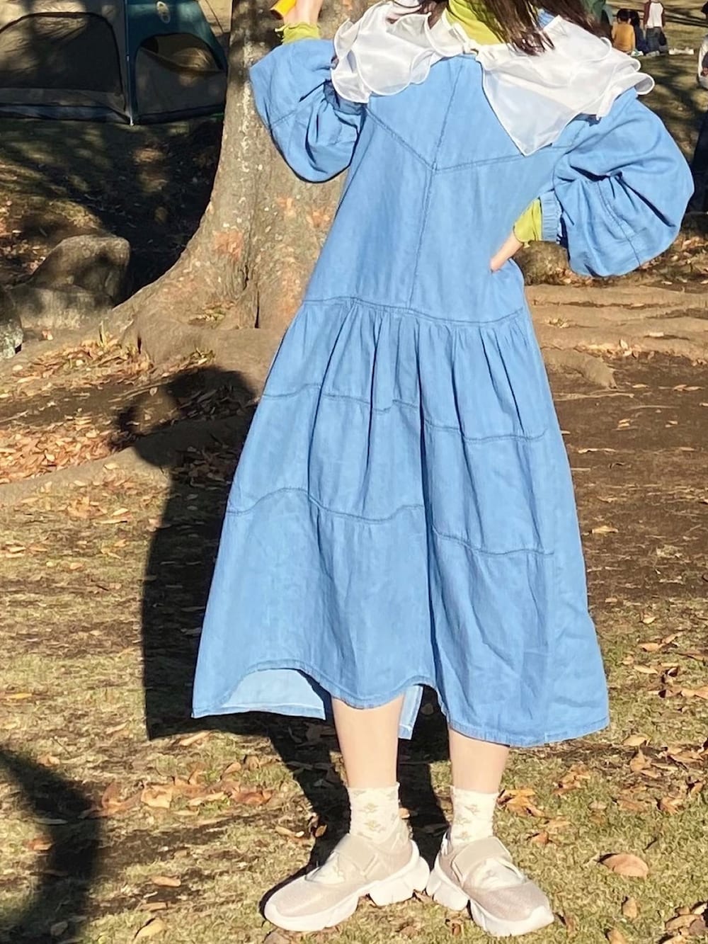 ベージュ系のスニーカー、ブルー系のワンピース、グリーン系のTシャツ/カットソーを着用したレディースの冬コーディネートの2枚目の写真