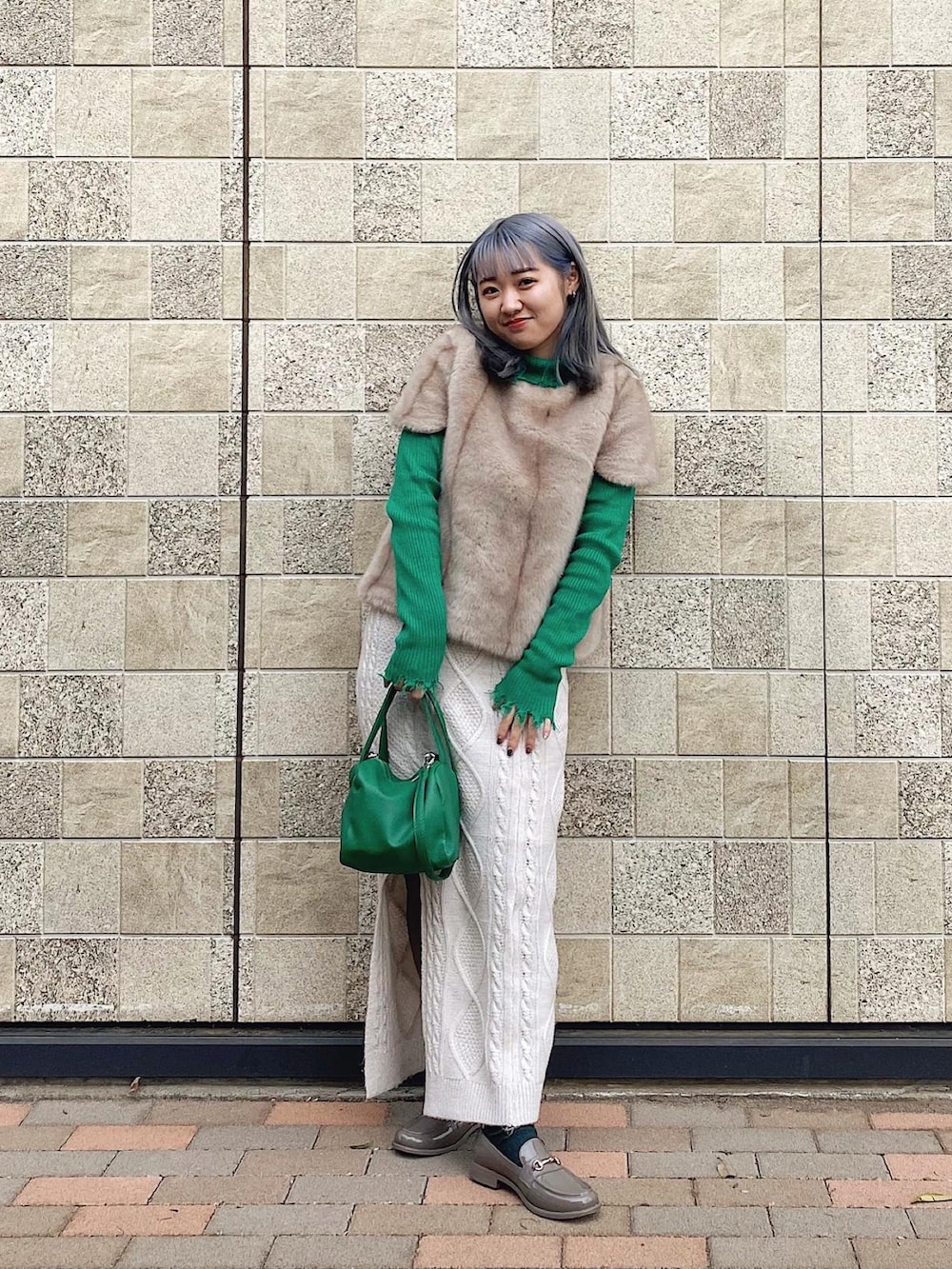 ホワイト系のスカート、グレー系のレインシューズ、グリーン系のバッグを着用したレディースの春コーディネートの2枚目の写真