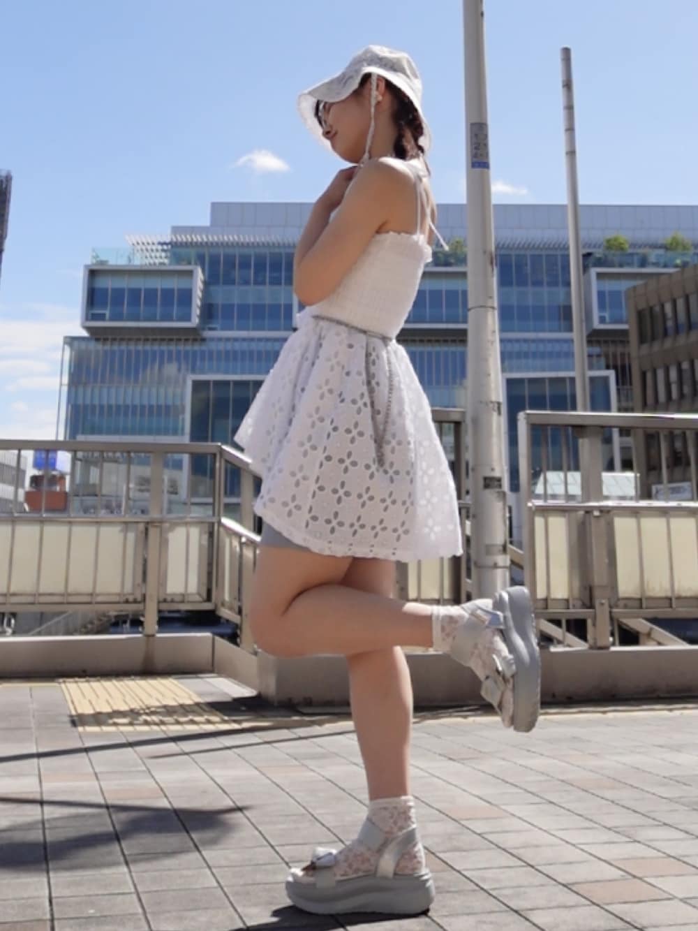 グレー系のサンダル、ブルー系のパンツ、ホワイト系のキャミソールを着用したレディースの夏コーディネートの2枚目の写真