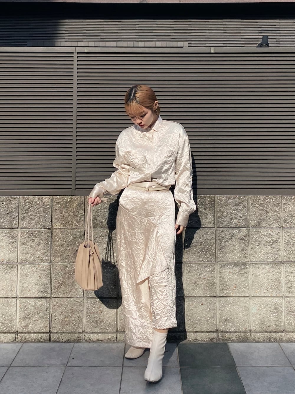 ホワイト系のスカート、ホワイト系のブーツ、ベージュ系のハンドバッグを着用したレディースの冬コーディネートの2枚目の写真