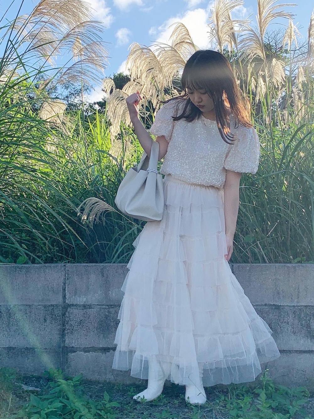 ホワイト系のトップス、ホワイト系のスカート、ホワイト系のブーツを着用したレディースの冬コーディネートの2枚目の写真