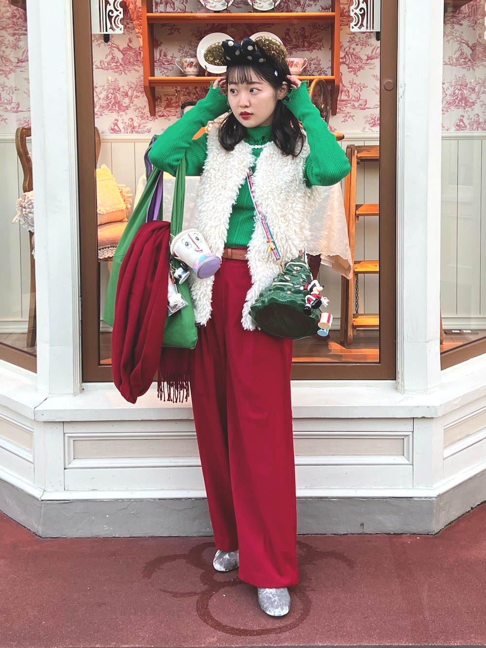 グリーン系のトートバッグ、レッド系のパンツ、シルバー系のブーツを着用したレディースの冬コーディネートの2枚目の写真