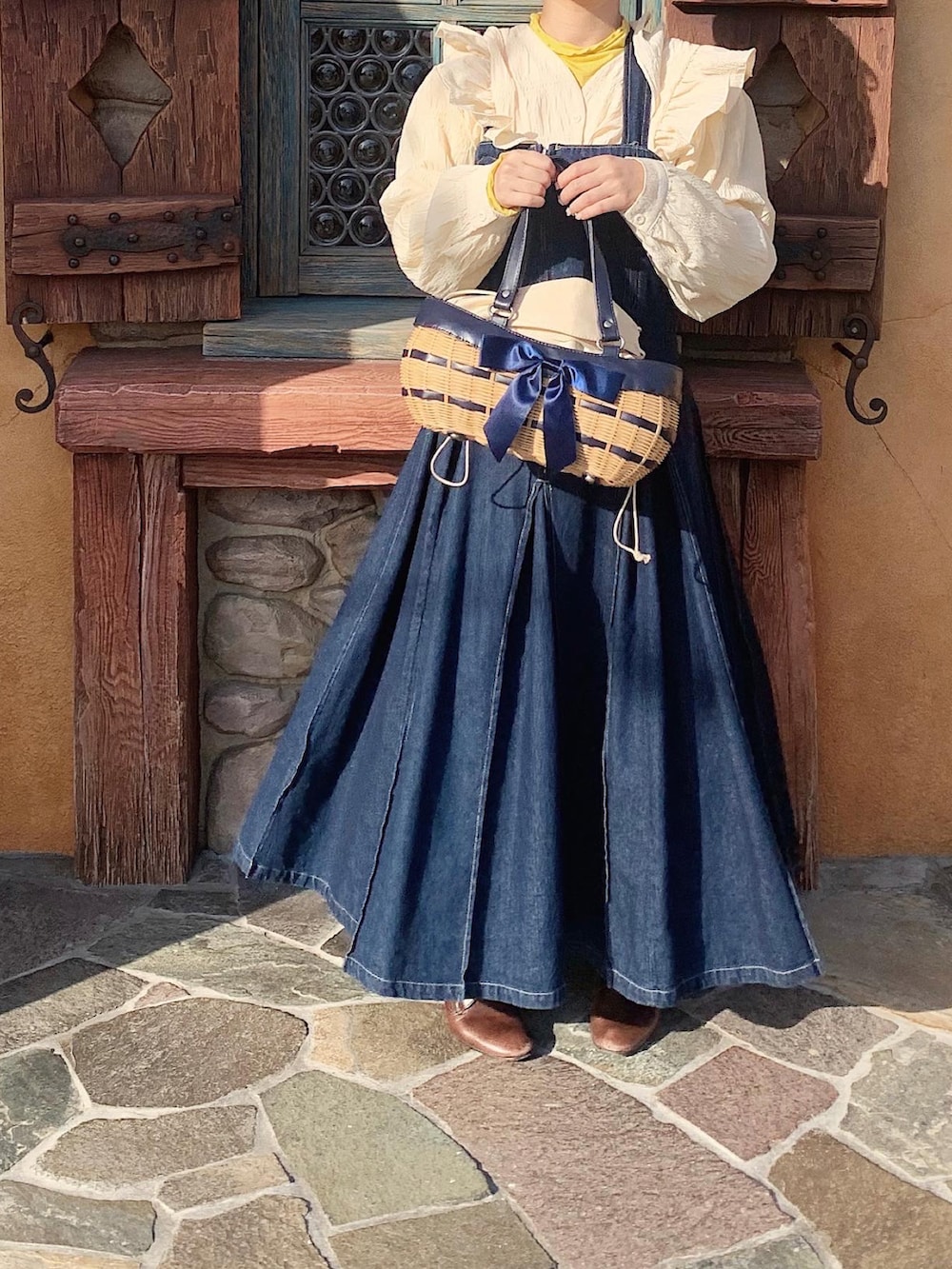 ブラウン系のブーツ、ベージュ系のトップス、ブルー系のかごバッグを着用したレディースの春コーディネートの3枚目の写真