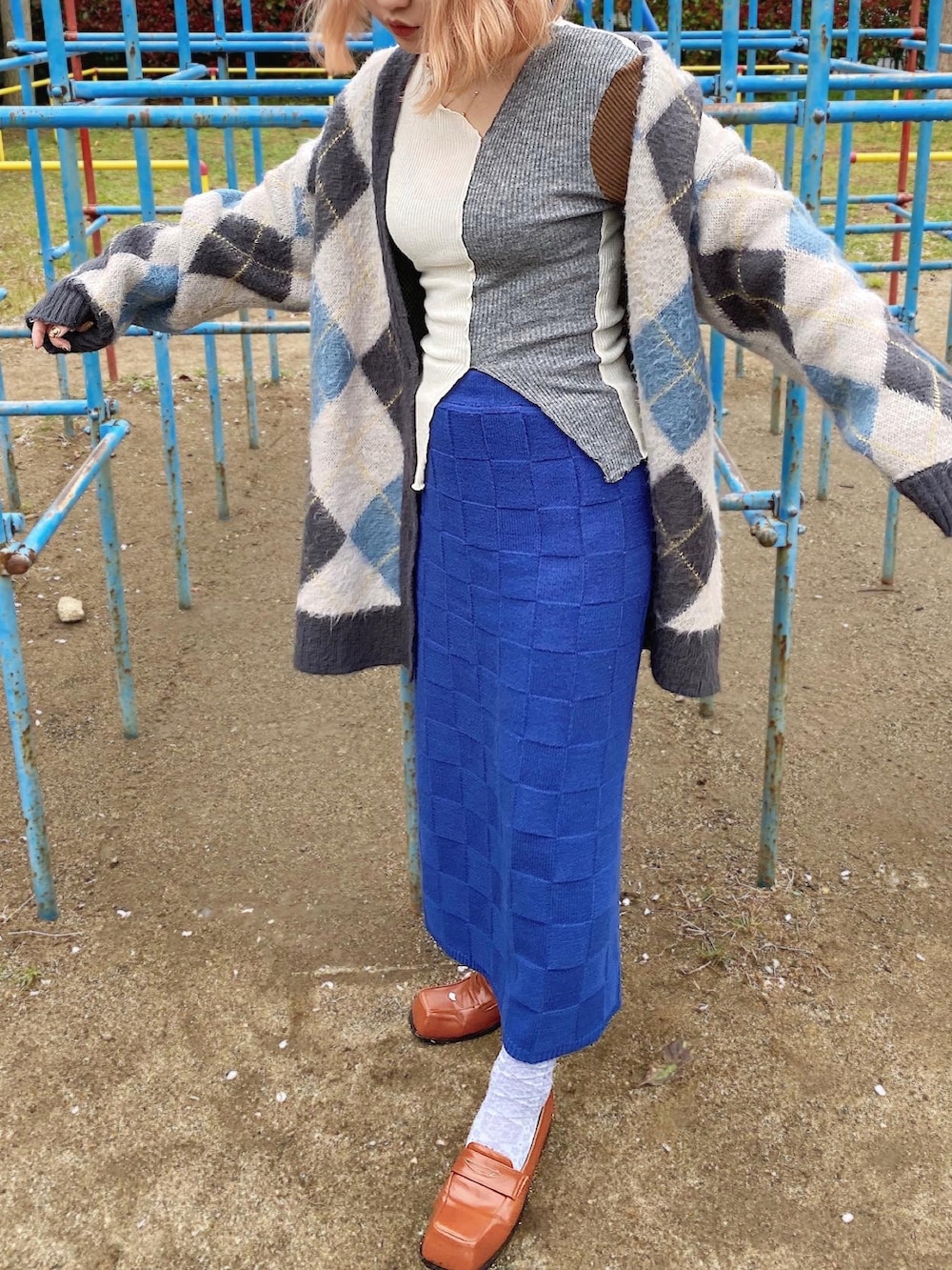 ブルー系のスカート、ブラウン系のローファー、グレー系のカーディガン/ボレロを着用したレディースの春コーディネートの2枚目の写真