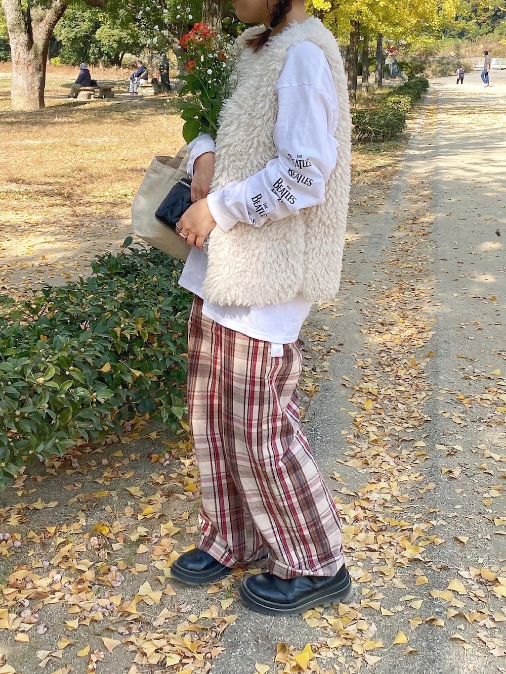 ブラック系のブーツ、ベージュ系のパンツ、ホワイト系のベストを着用したレディースの冬コーディネートの2枚目の写真