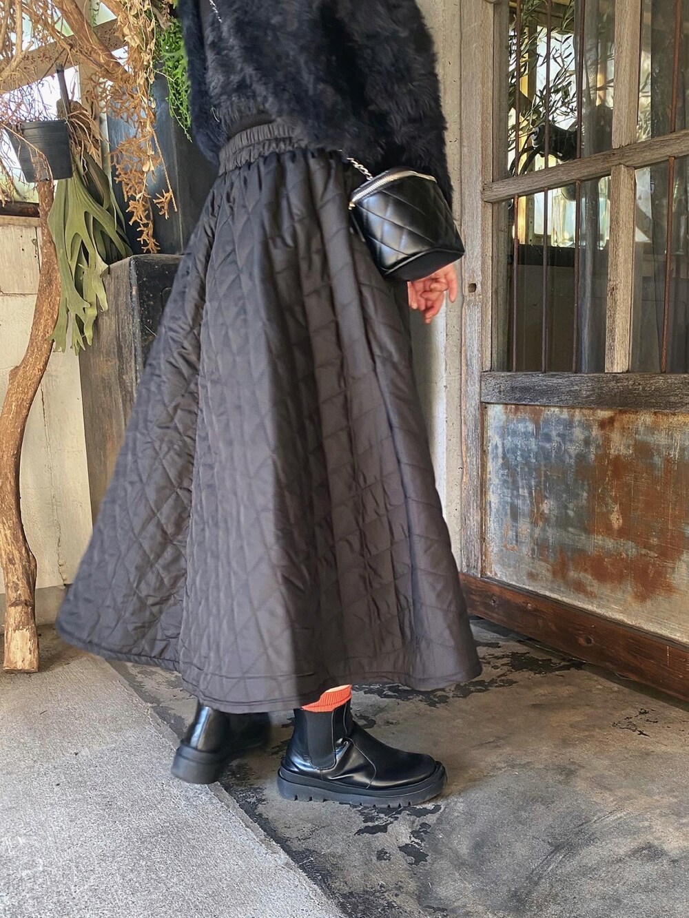 ブラック系のスカート、ブラック系のカーディガン/ボレロ、ブラック系のバッグを着用したレディースの冬コーディネートの3枚目の写真