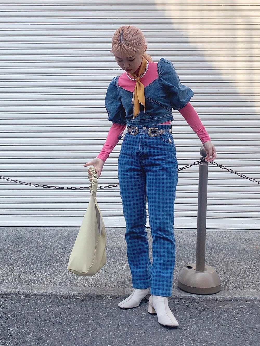 イエロー系のトレンチコート、ブルー系のデニムパンツ、ベージュ系のブーツを着用したレディースの春コーディネートの4枚目の写真