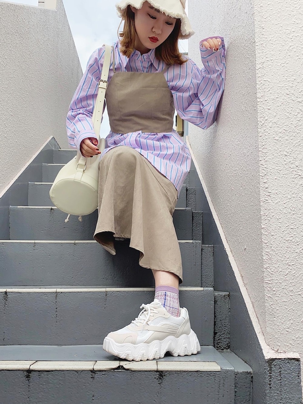 ベージュ系のワンピース、ホワイト系のバッグ、ホワイト系のスニーカーを着用したレディースの秋コーディネートの3枚目の写真