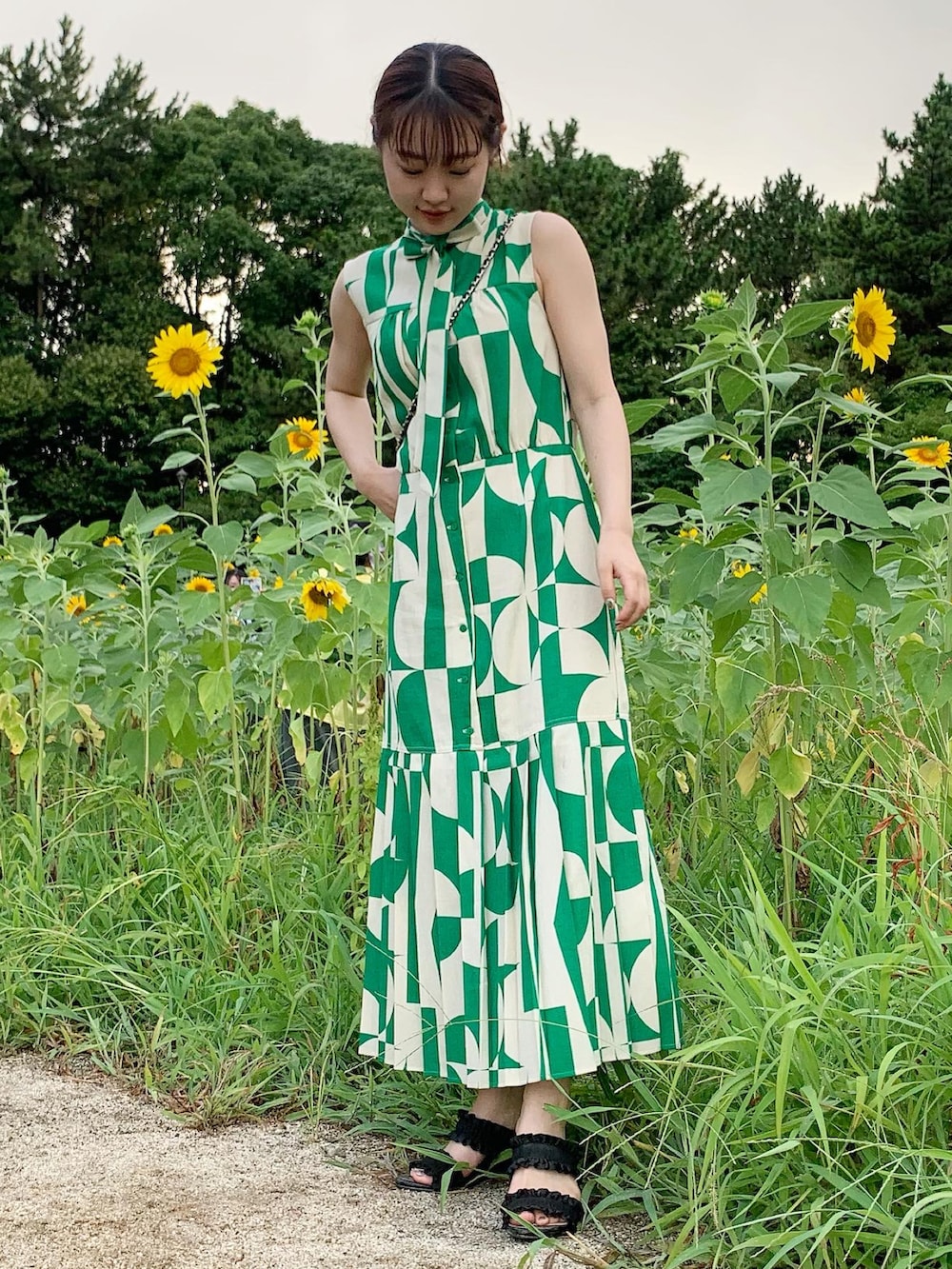 グリーン系のワンピース、ブラック系のサンダル、ブラック系のバッグを着用したレディースの夏コーディネートの2枚目の写真