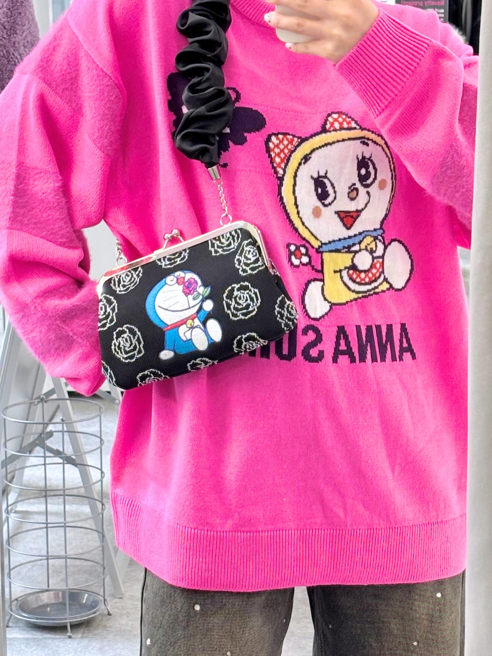 ブラック系のショルダーバッグ、ブラック系のデニムパンツ、ピンク系のトップスを着用したレディースの秋コーディネートの2枚目の写真