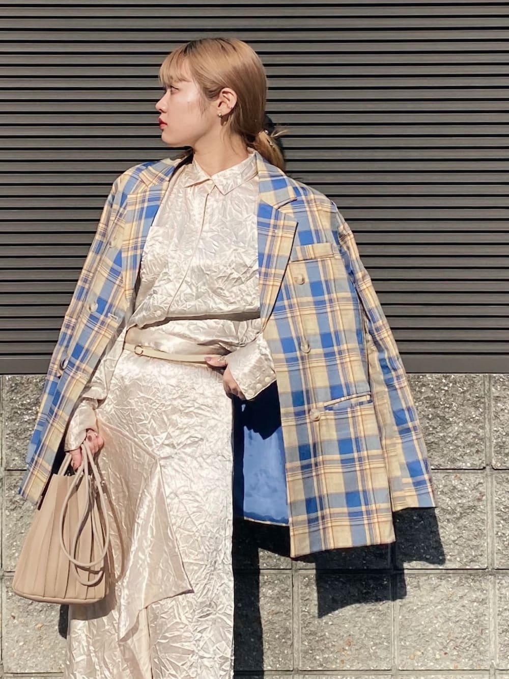 ホワイト系のスカート、ホワイト系のブーツ、ベージュ系のハンドバッグを着用したレディースの冬コーディネートの3枚目の写真