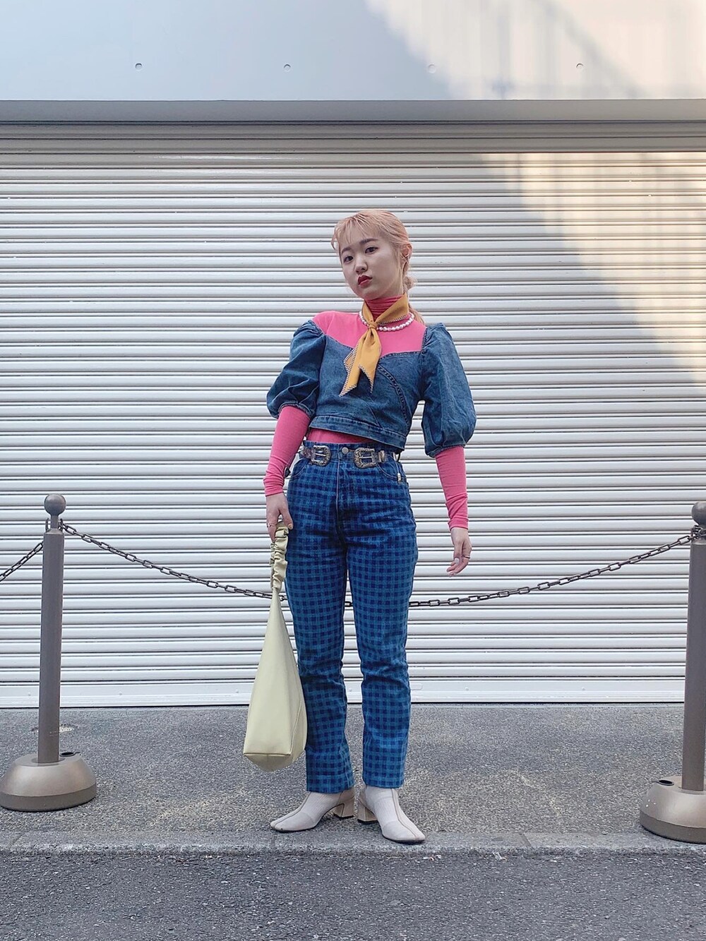 イエロー系のトレンチコート、ブルー系のデニムパンツ、ベージュ系のブーツを着用したレディースの春コーディネートの3枚目の写真