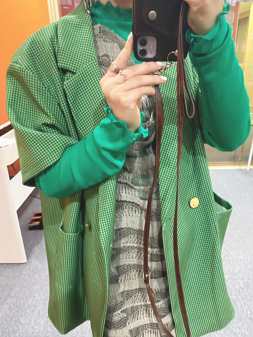 グリーン系のテーラードジャケット、グレー系のワンピース/ドレス、シルバー系のスカートを着用したレディースの春コーディネートの2枚目の写真