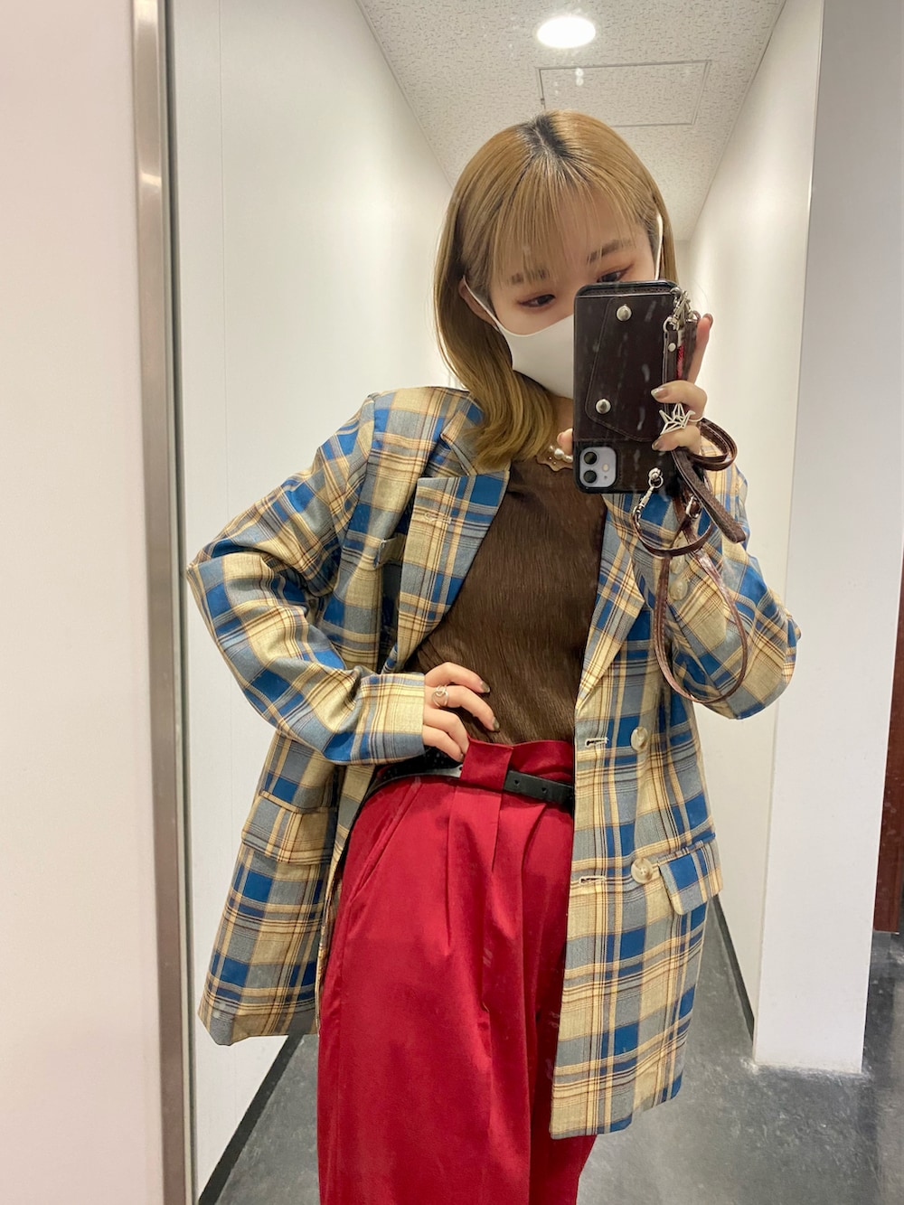 レッド系のパンツ、ブルー系のテーラードジャケット、ブラウン系のトップスを着用したレディースの秋コーディネートの2枚目の写真