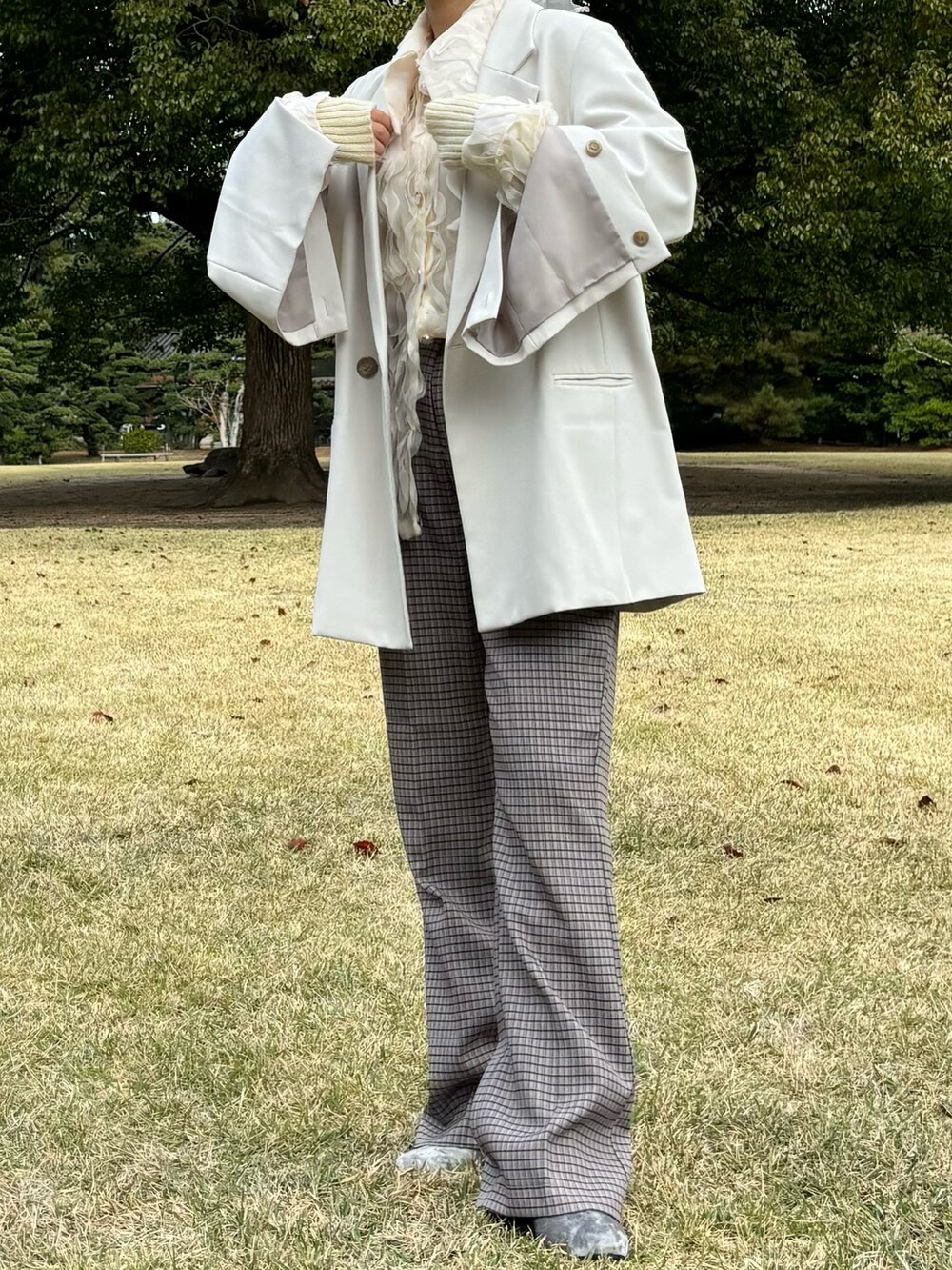 ベージュ系のスラックス、シルバー系のブーツ、グレー系のジャケット/アウターを着用したレディースの冬コーディネートの2枚目の写真