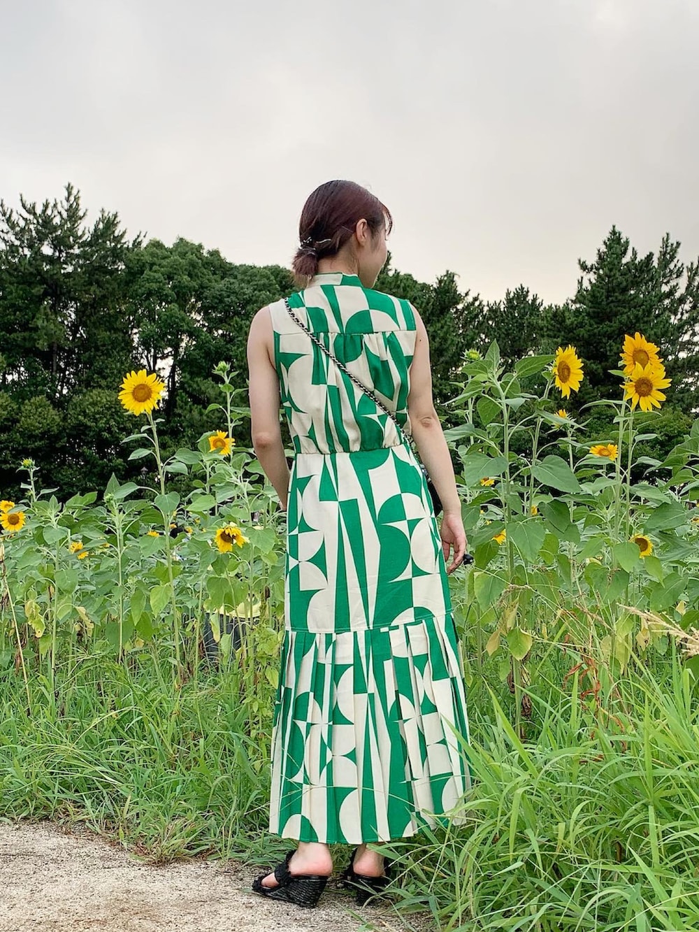 グリーン系のワンピース、ブラック系のサンダル、ブラック系のバッグを着用したレディースの夏コーディネートの3枚目の写真