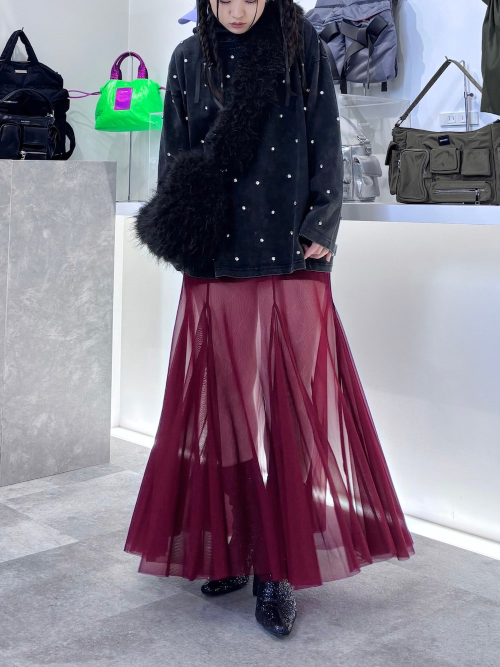 レッド系のスカート、ブラック系のTシャツ/カットソー、ブラック系のショルダーバッグを着用したレディースの秋コーディネートの2枚目の写真