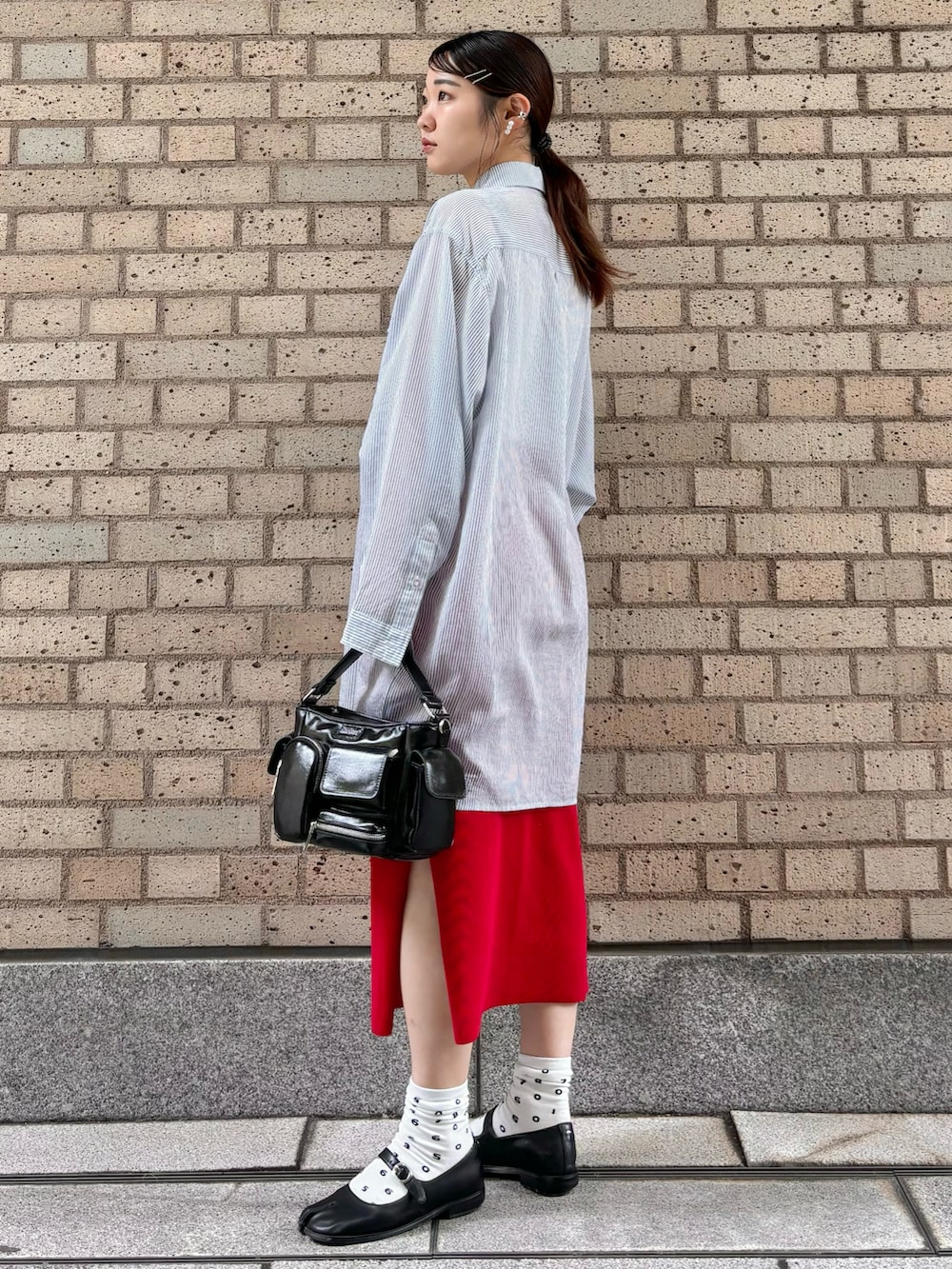 ブルー系のシャツ/ブラウス、ブラック系のショルダーバッグ、レッド系のスカートを着用したレディースの春コーディネートの2枚目の写真