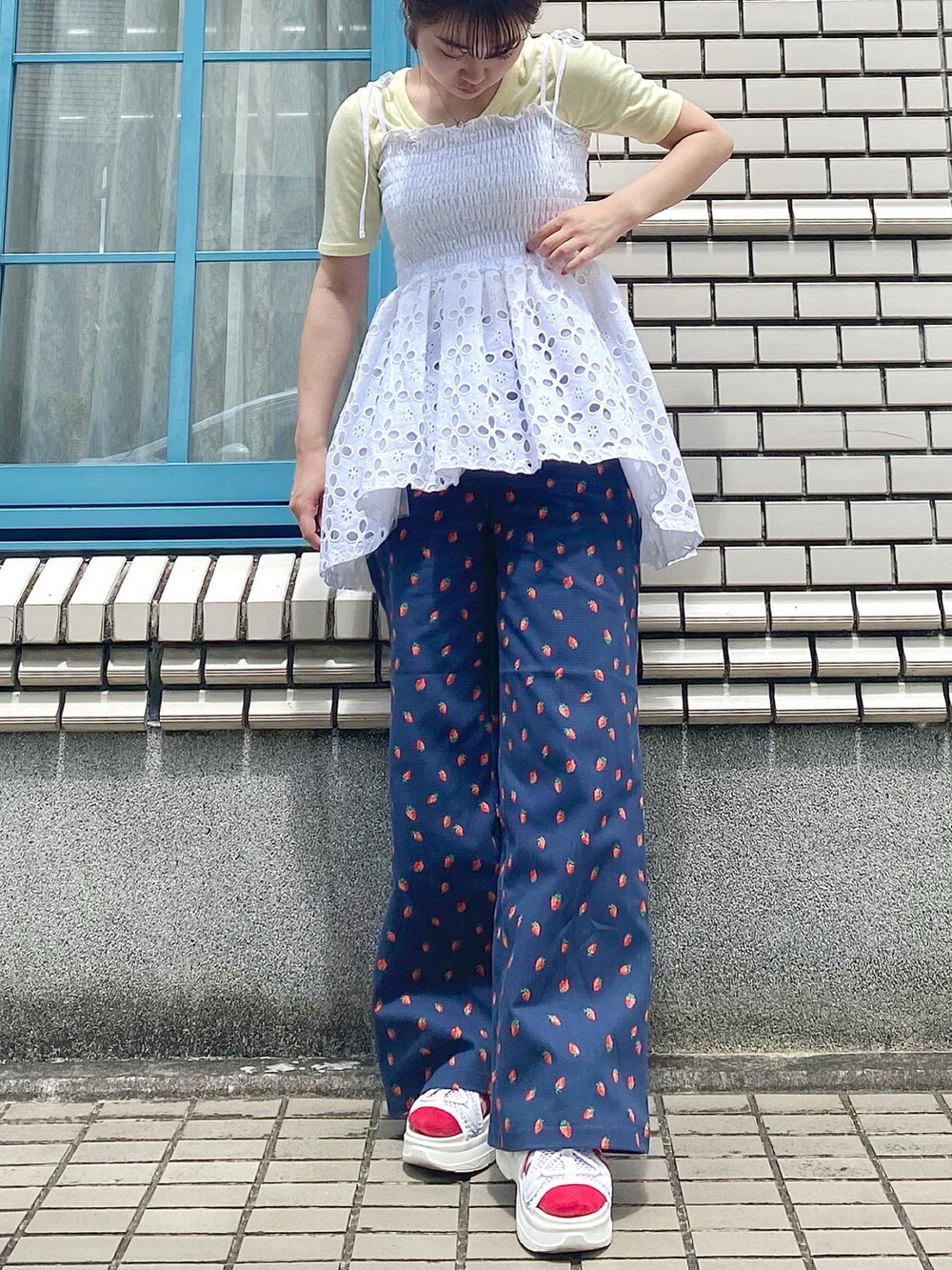 ブルー系のデニムパンツ、ホワイト系のサンダル、ホワイト系のキャミソールを着用したレディースの夏コーディネートの2枚目の写真