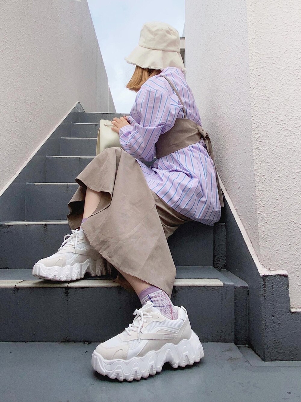 ベージュ系のワンピース、ホワイト系のバッグ、ホワイト系のスニーカーを着用したレディースの秋コーディネートの5枚目の写真