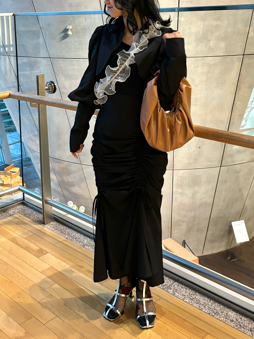 ブラック系のスカート、ブラウン系のハンドバッグ、ブラック系のノーカラージャケットを着用したレディースの秋コーディネートの2枚目の写真